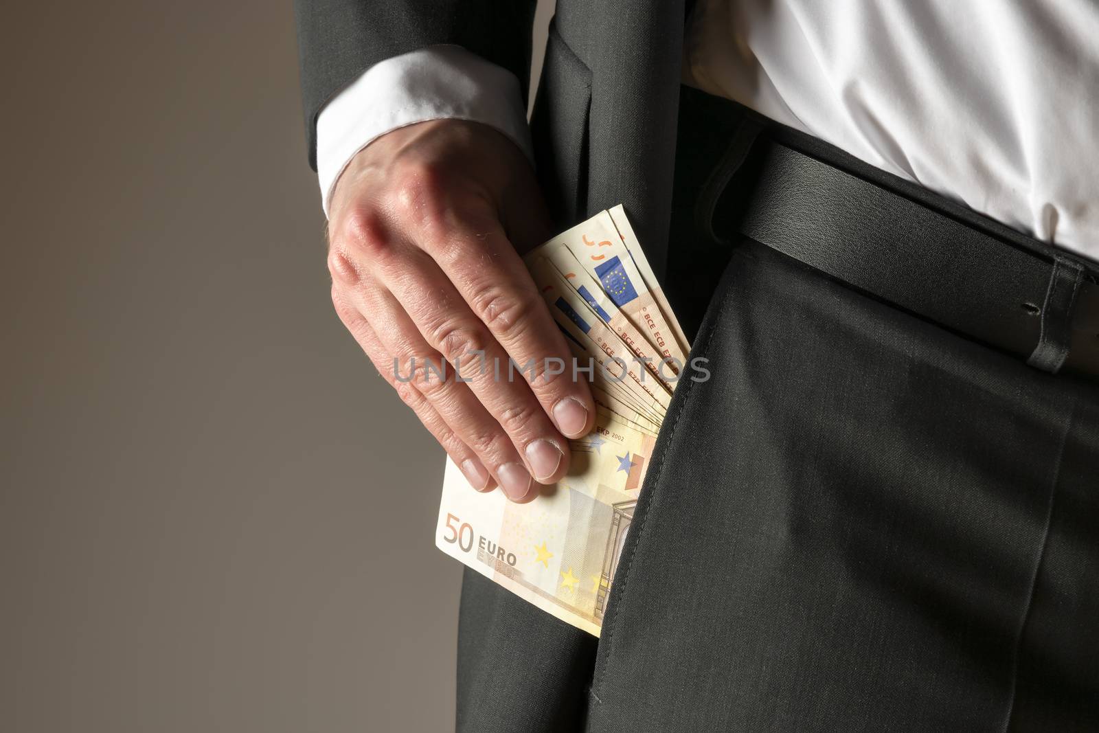 Businessman in dark suit and with tie putting money in his pocket