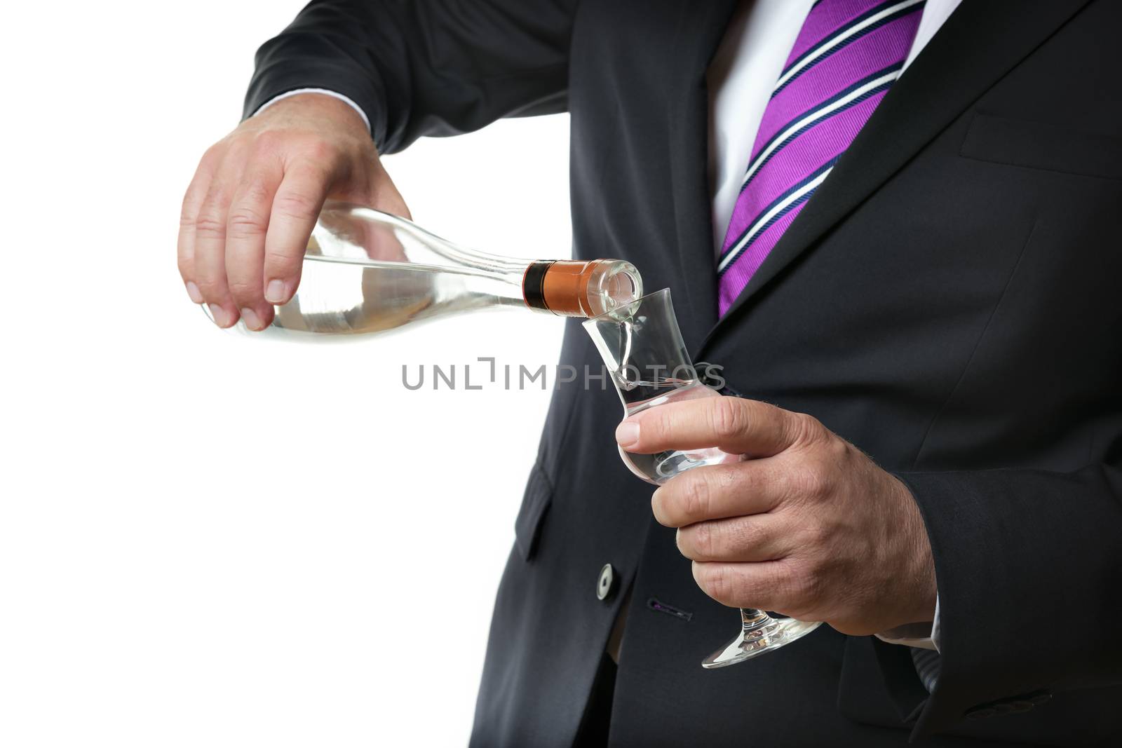 Business man in dark suite with a grappa glas and a bottle with alcohol