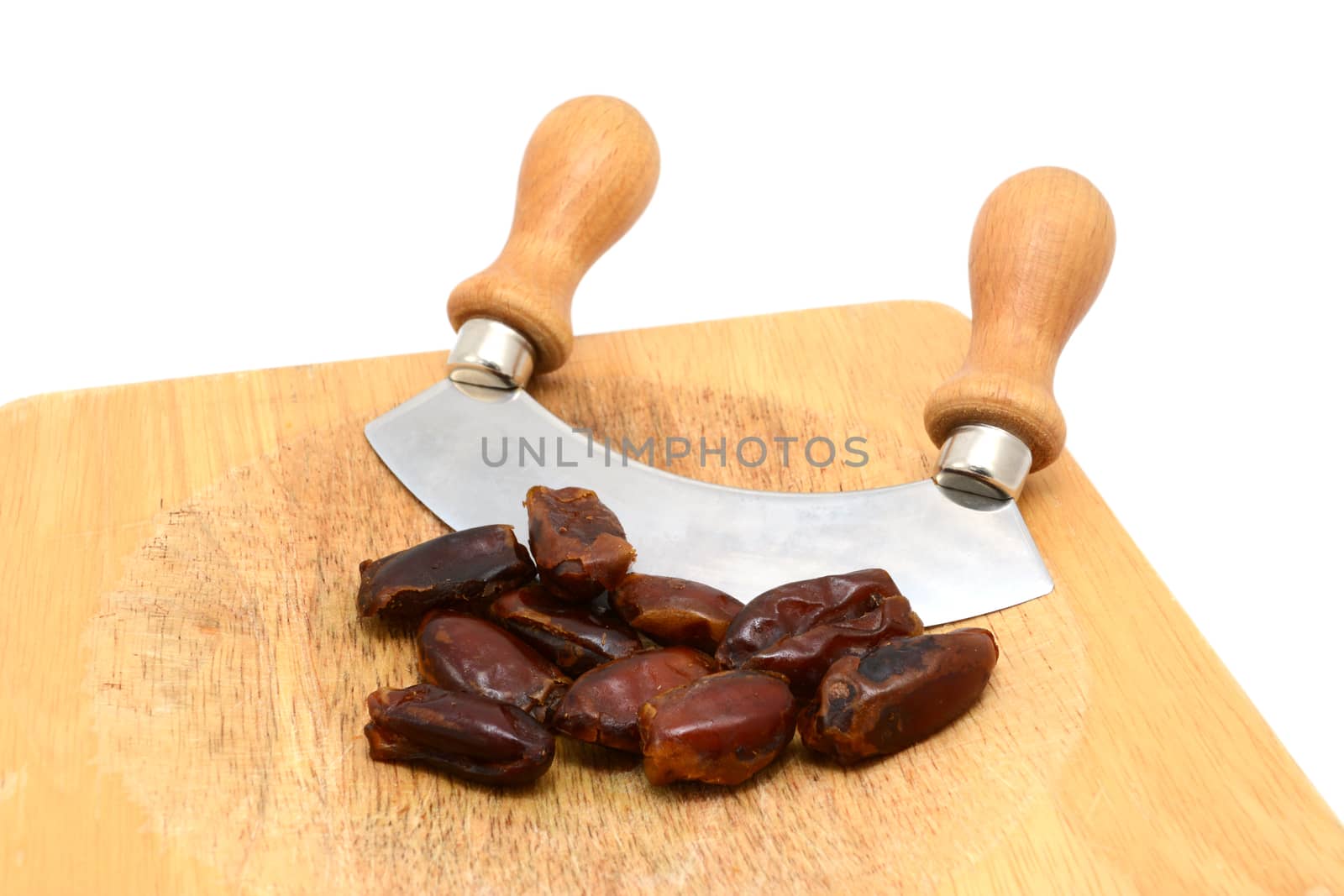 Whole dates with a rocking knife on a wooden chopping board