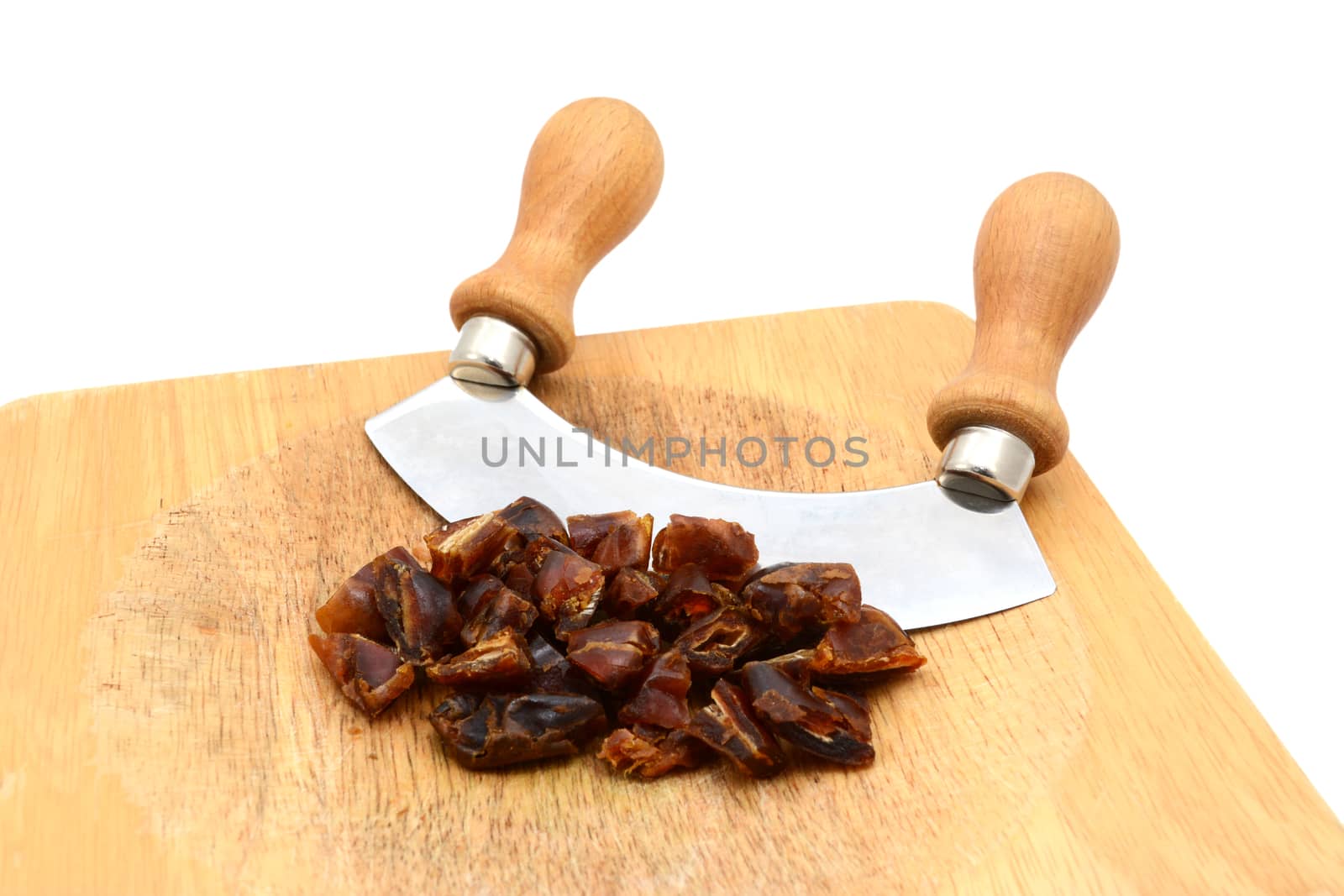 Chopped dates with a rocking knife on a wooden chopping board