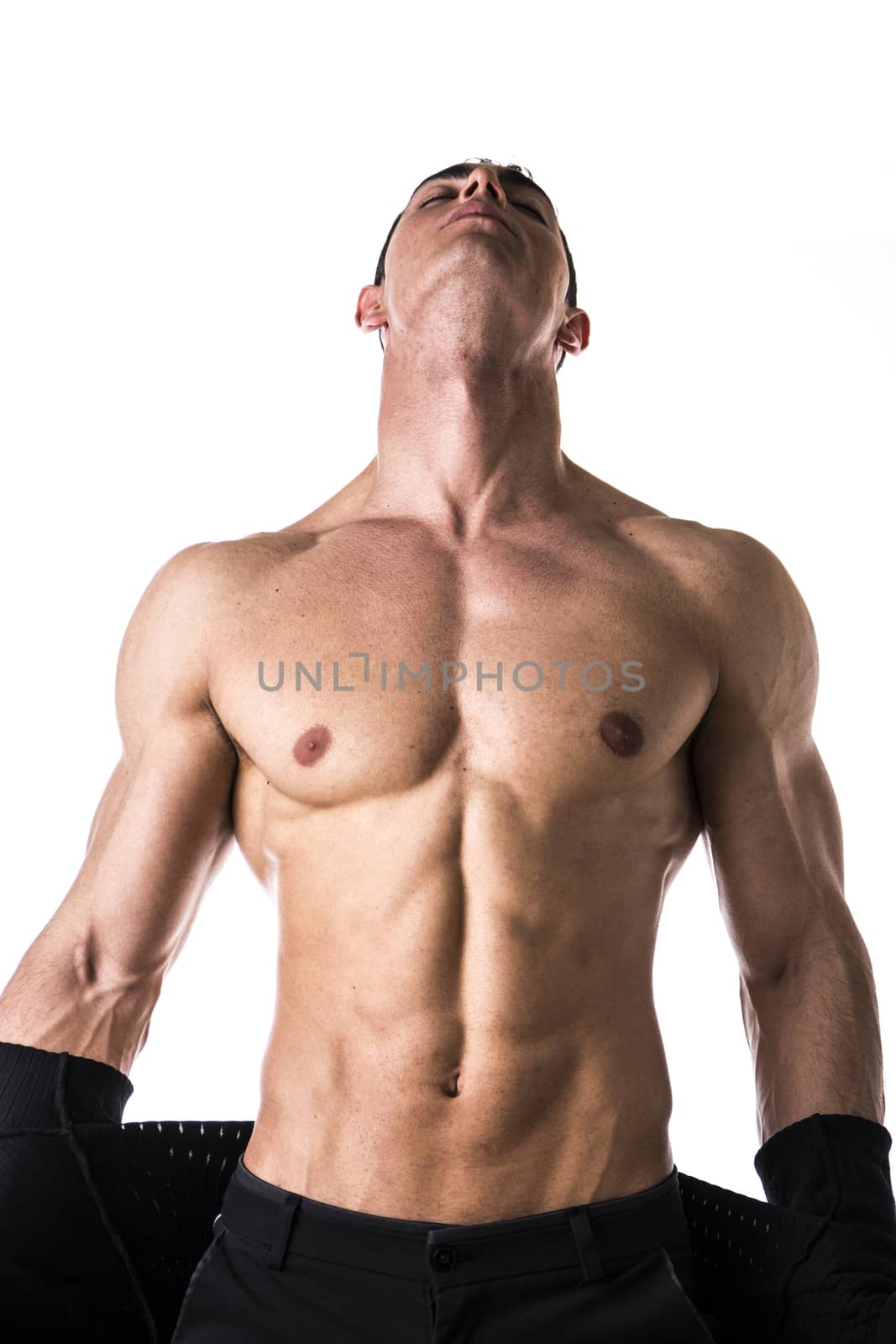 Handsome muscular young man taking off shirt, isolated on white, looking up