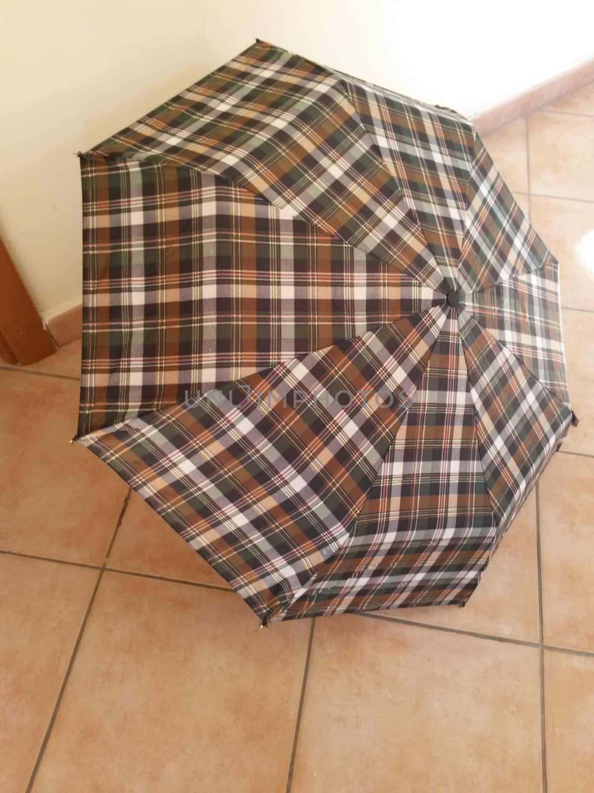 Tartan umbrella open over red brick floor tiles