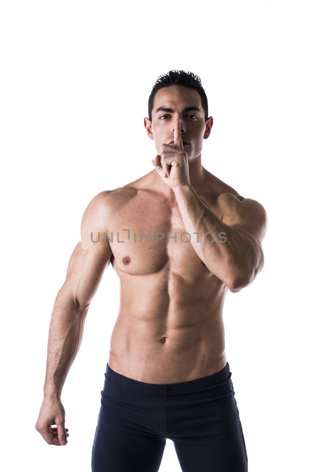 Muscular shirtless young man doing shut up sign with finger on lips