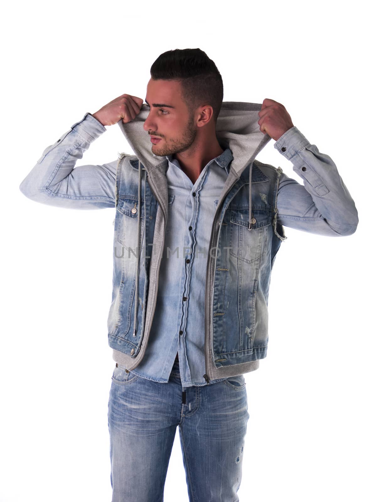 Handsome young man in hoodie, denim vest and jeans, isolated on white