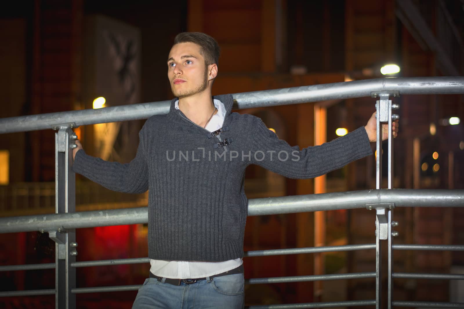 Handsome blond young man alone in urban setting, looking away, night shot