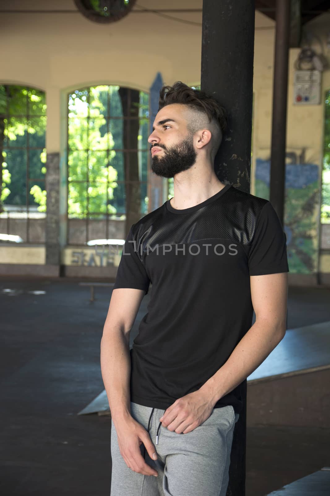Handsome young man with beard leaning against black pole