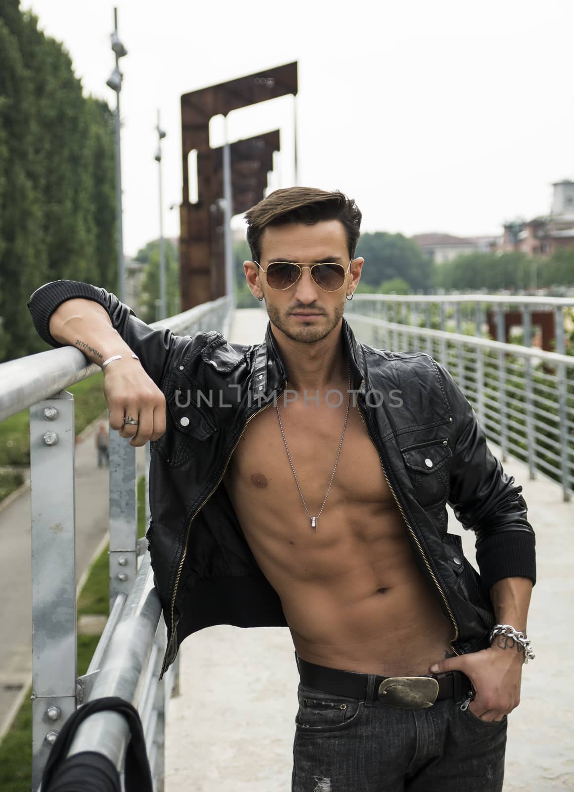 Handsome man outdoor in urban environment wearing leather jacket on naked torso