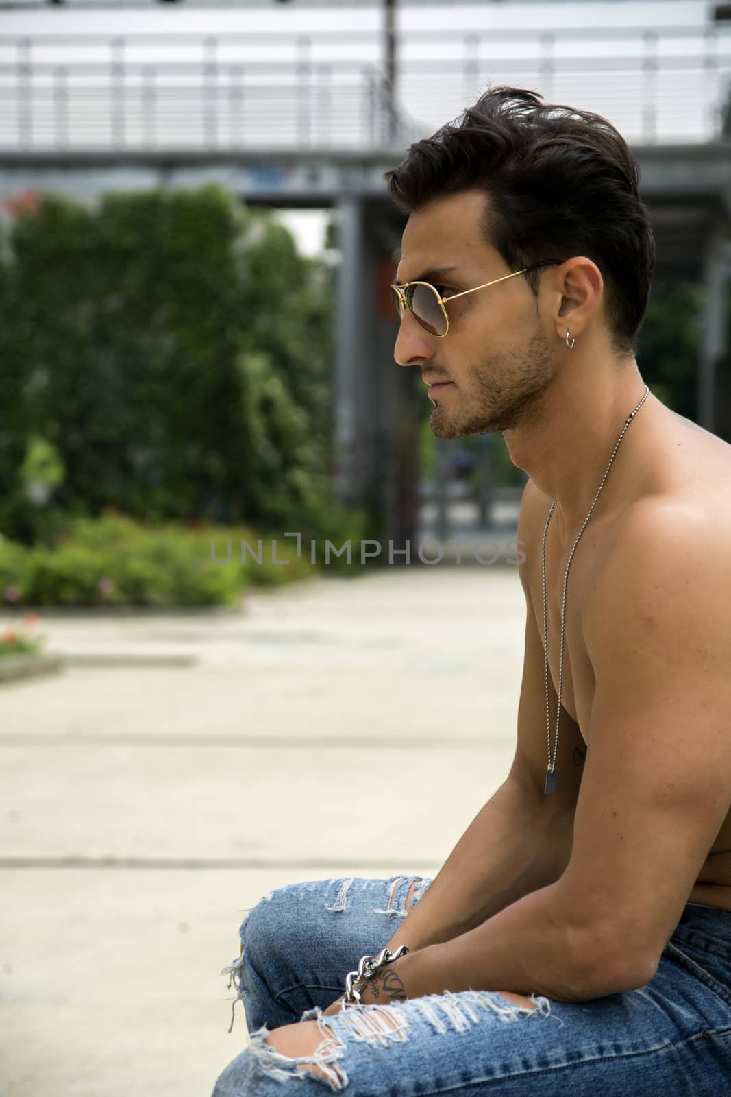 Handsome shirtless man outdoor in urban environment, profile shot