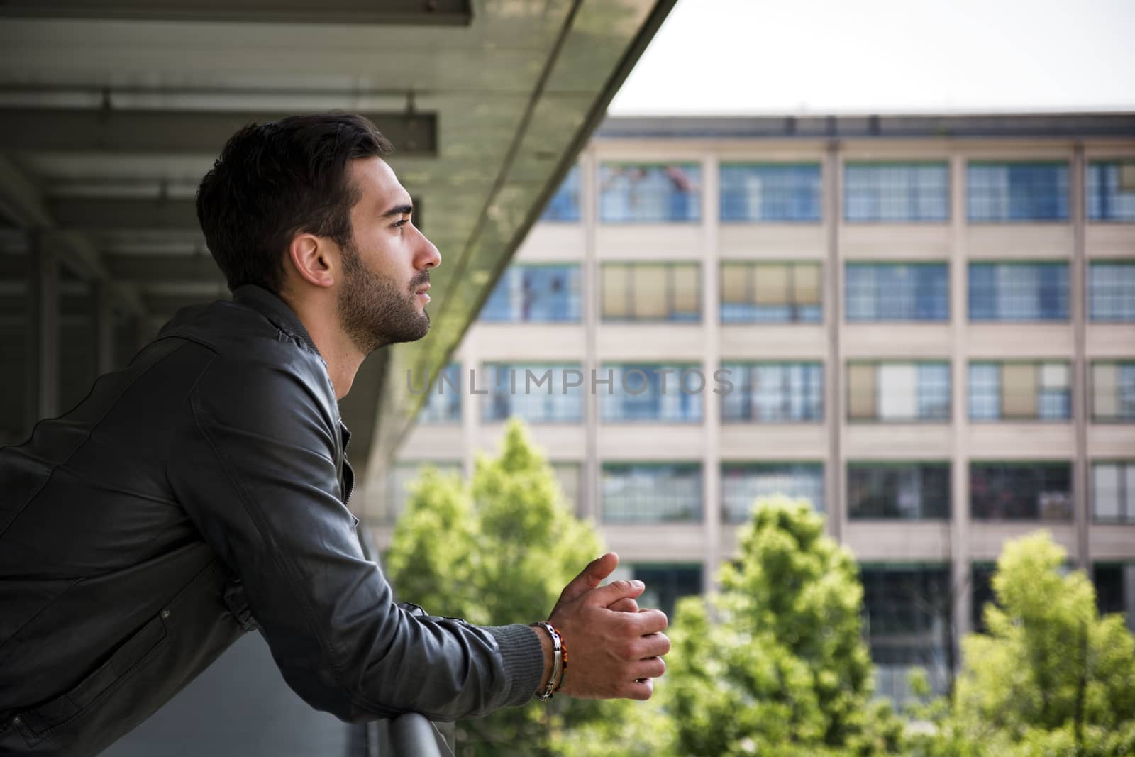 Profile  shot of attractive bearded young man in city, looking afar outdoors