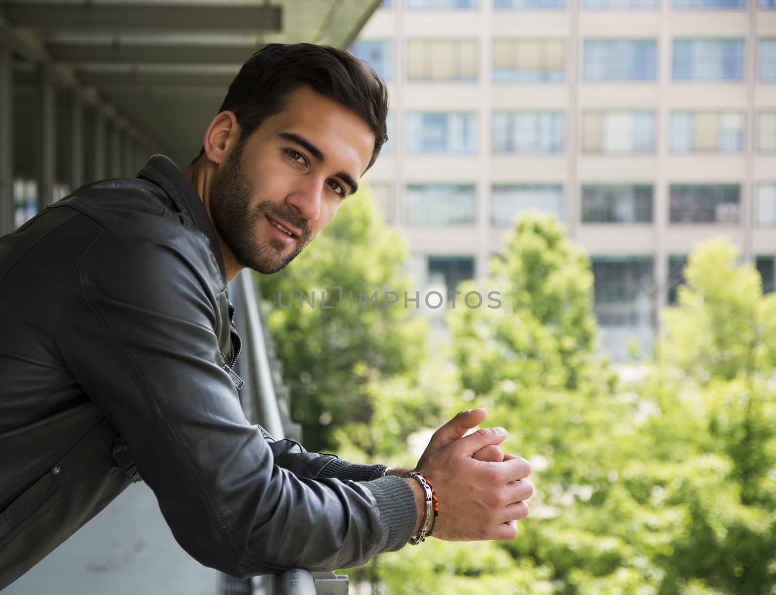 Profile  shot of attractive bearded young man in city, looking at camera outdoors