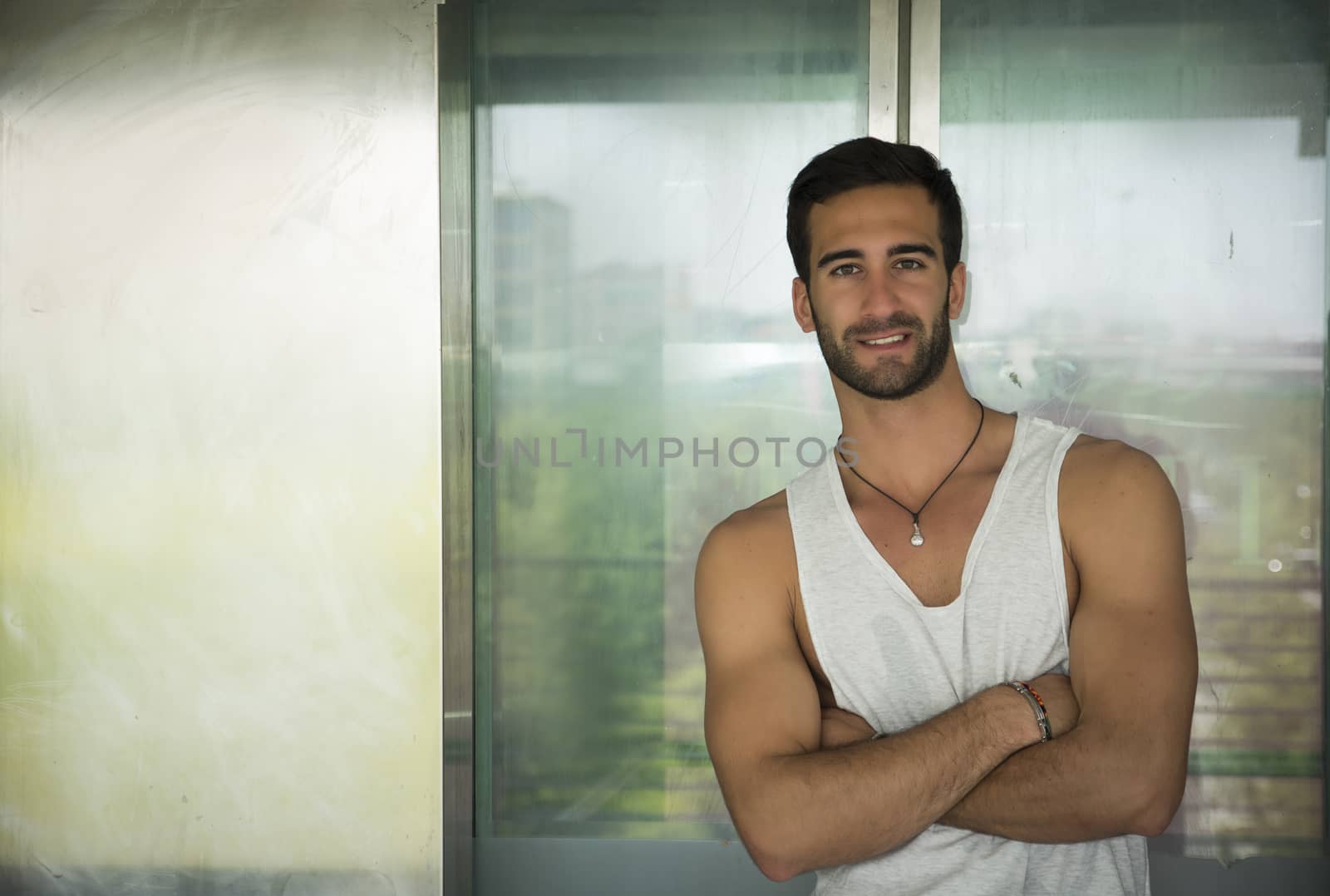 Handsome bearded young man outdoors in urban environment smiling and  looking at camera