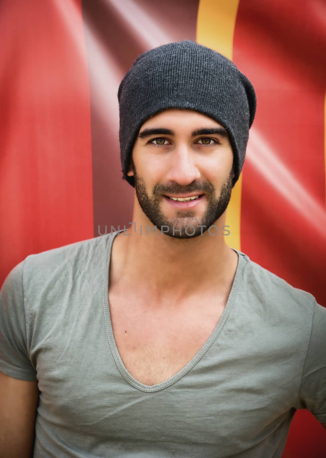 Handsome bearded young man smiling on colorful background, looking at camera