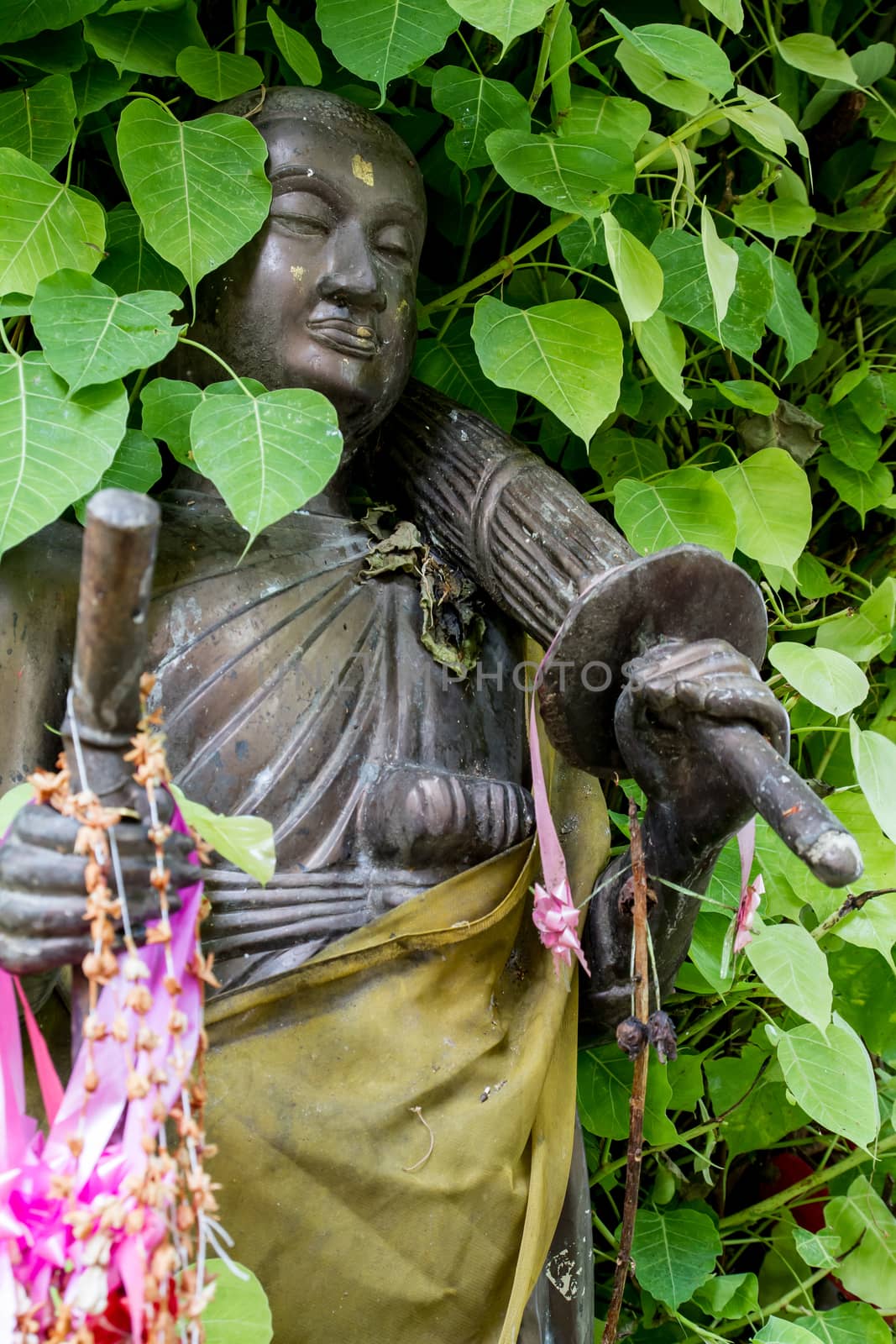 Thai monk statue in temple with Bo leaves around