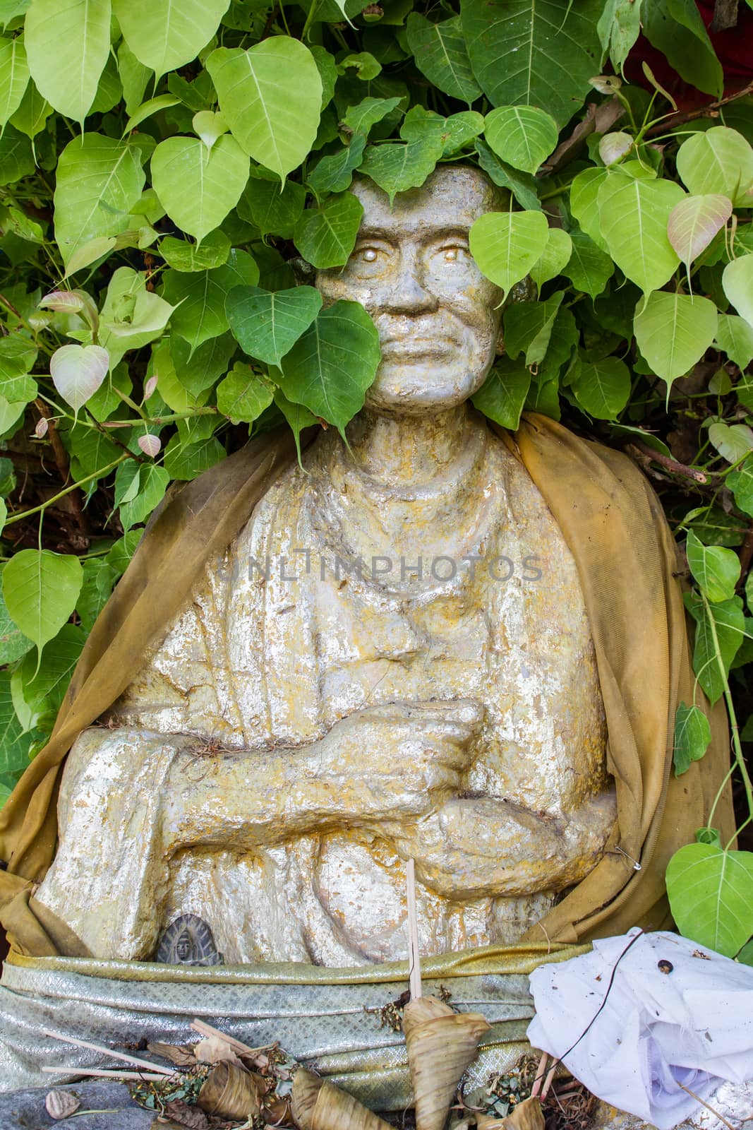 Thai monk statue in temple with Bo leaves around