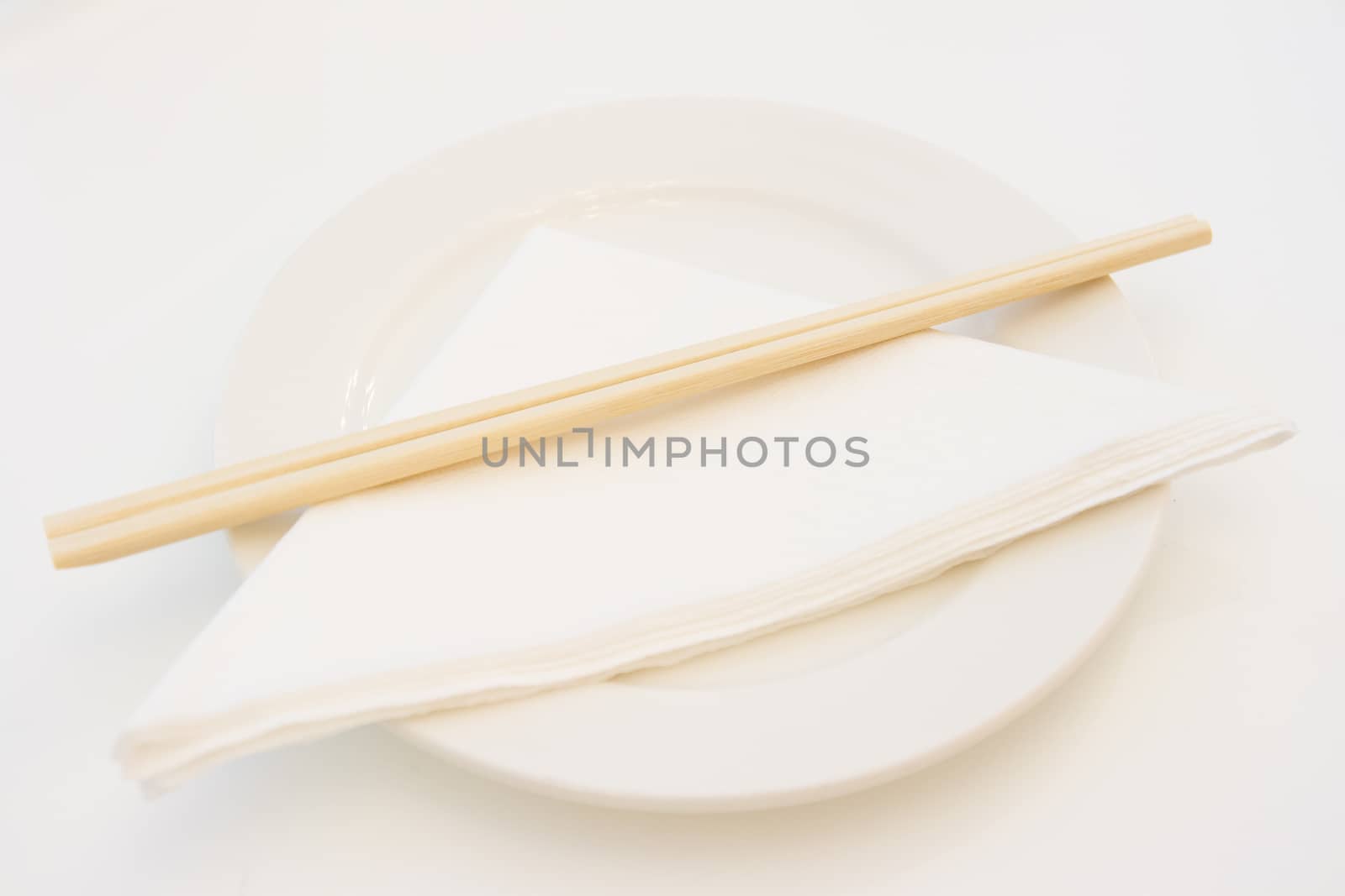 White plate with wooden chopsticks and paper napkin on, shallow depth of field