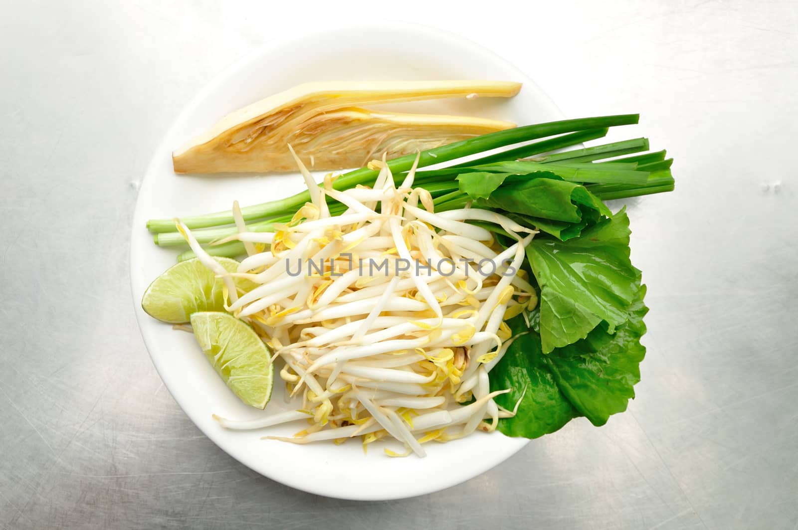 Mix of Thai Vegetable, Bean sprout, lime, banana blossom and Garlic chives on white plate.
