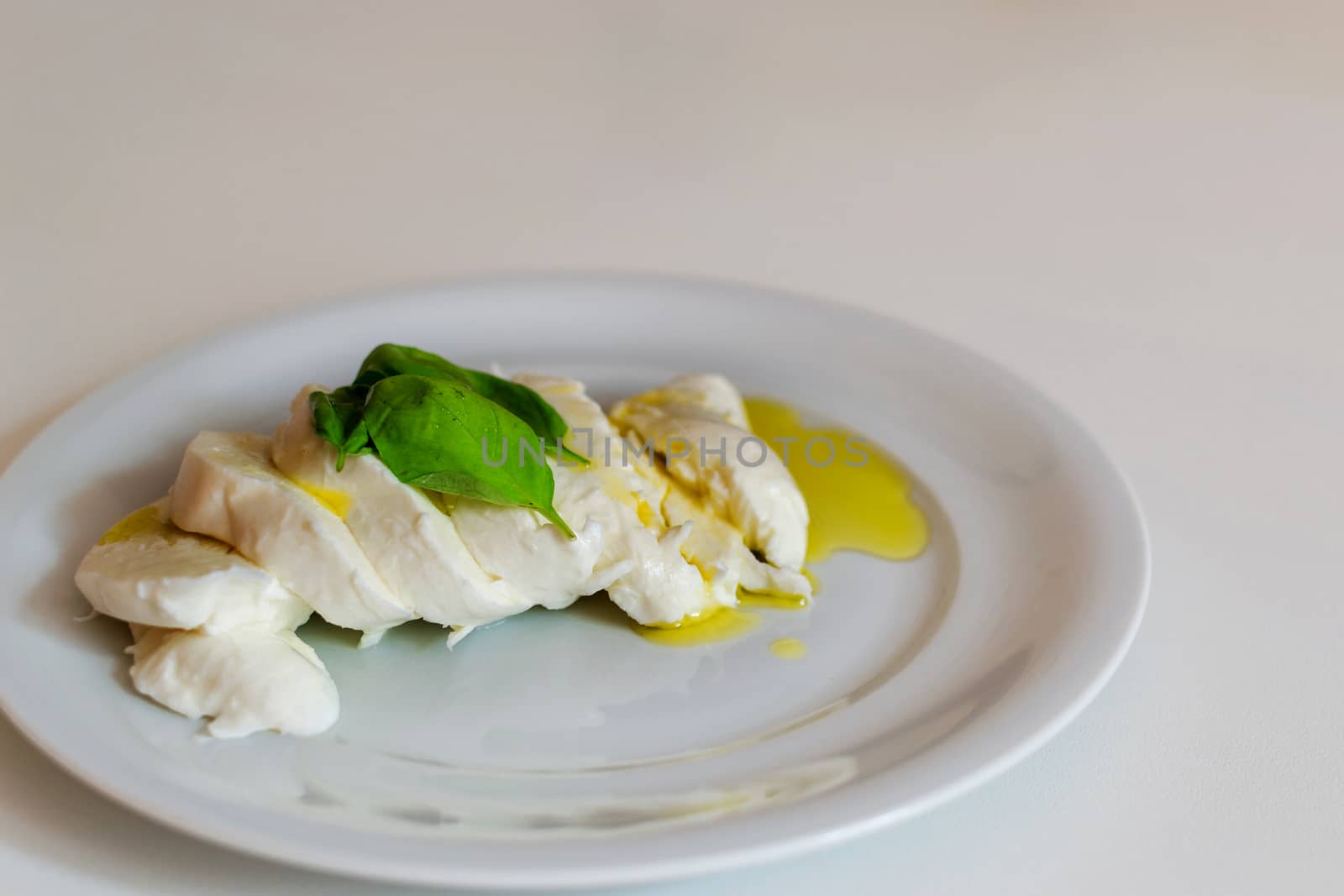 Slices of italian mozzarella with leaves of basil and olive oil by enrico.lapponi