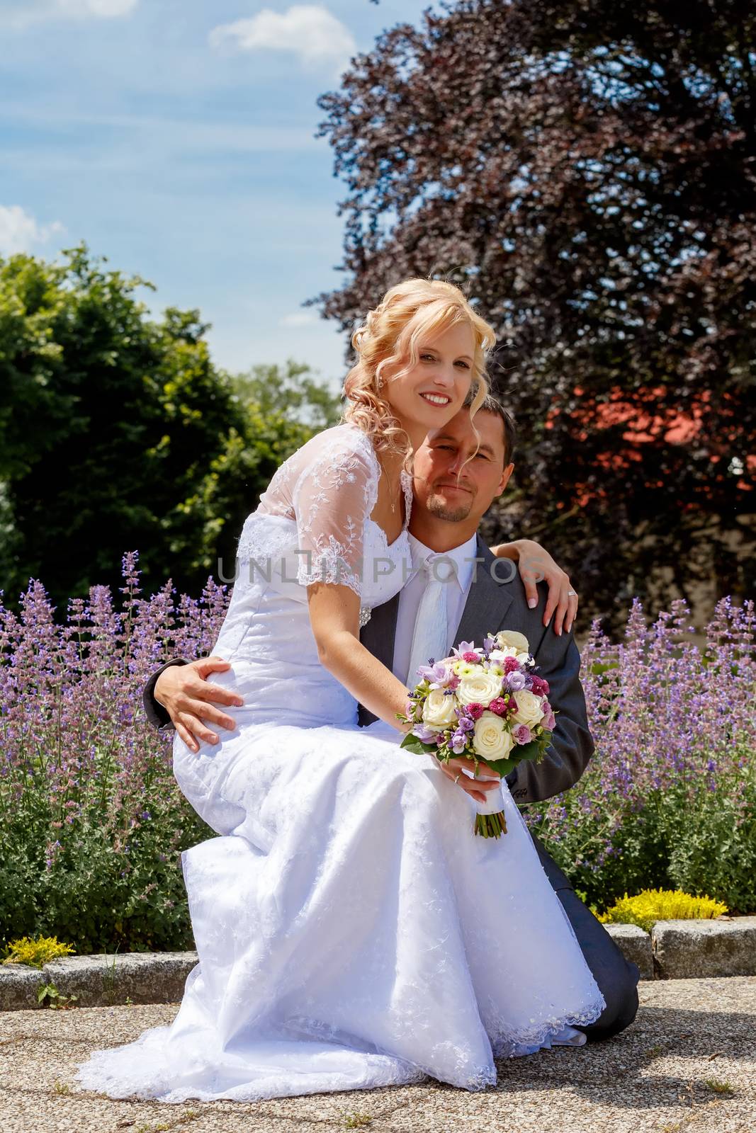 beautiful young wedding couple, blonde bride and her groom against lavender flower