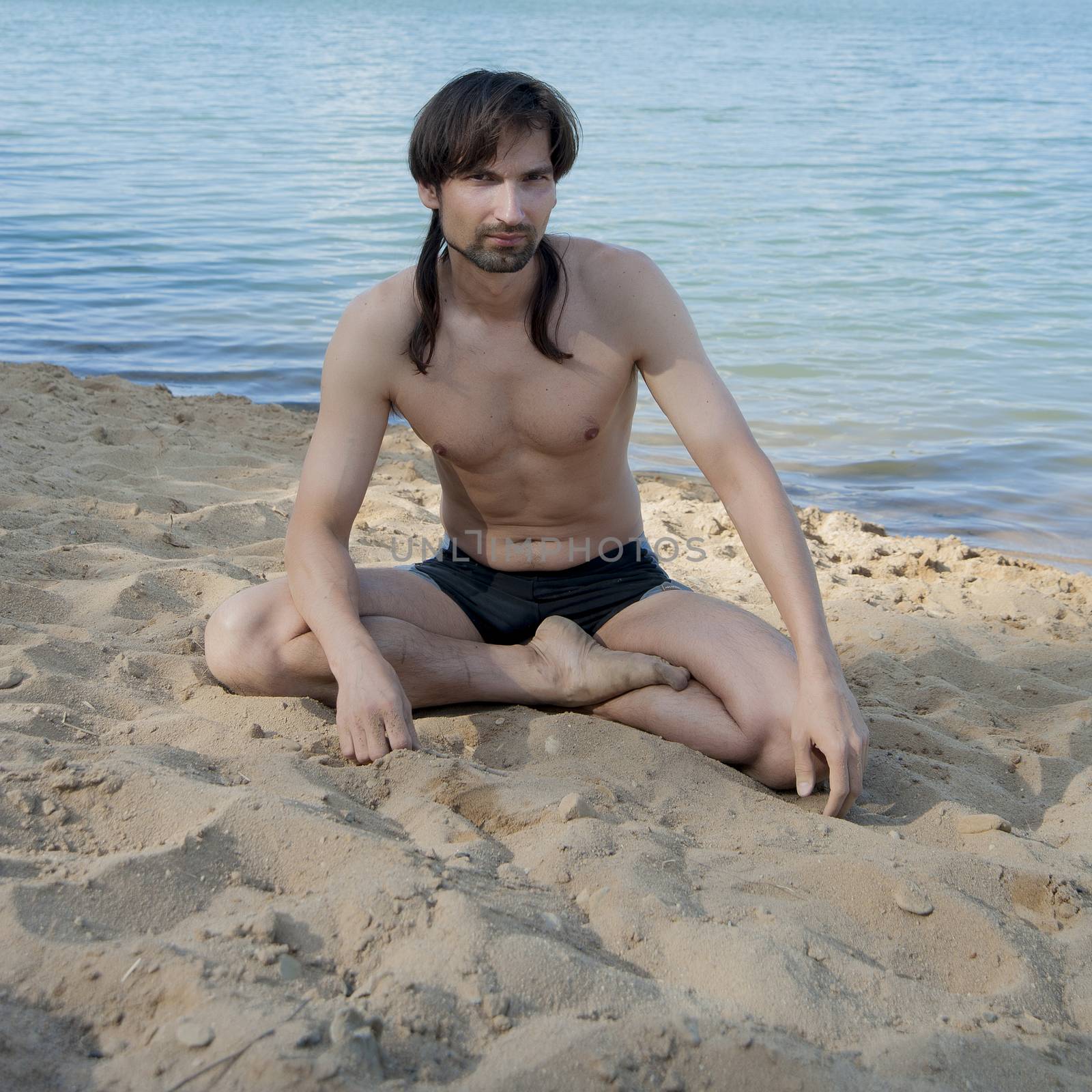 man in a bathing suit on the beach in the sand in the summer