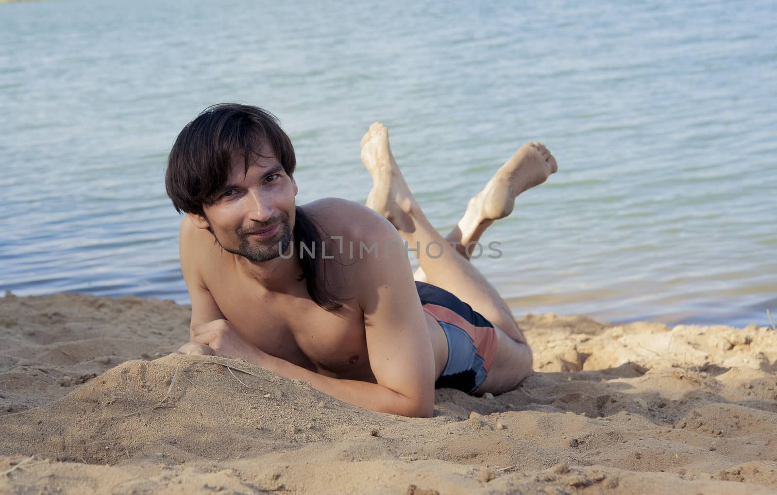 man in a bathing suit on the beach in the sand in the summer