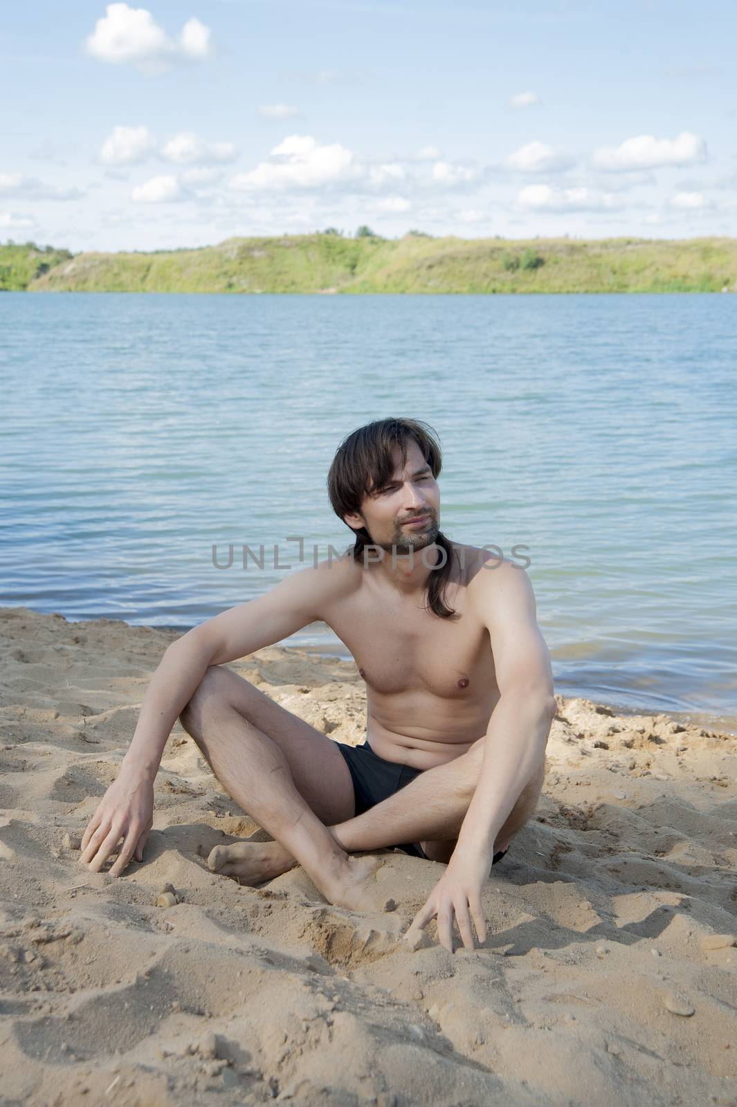 man in a bathing suit on the beach in the sand in the summer