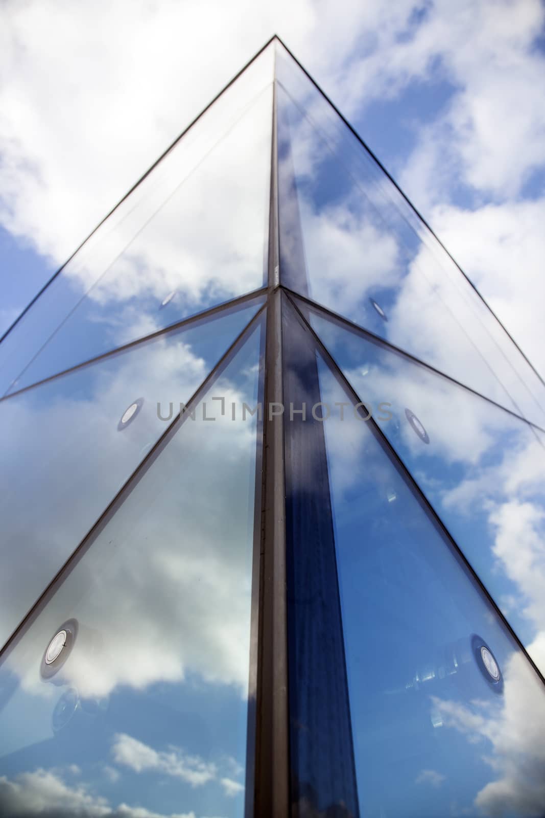 reflexions of clouds and blue sky in facade of modern building by ahavelaar