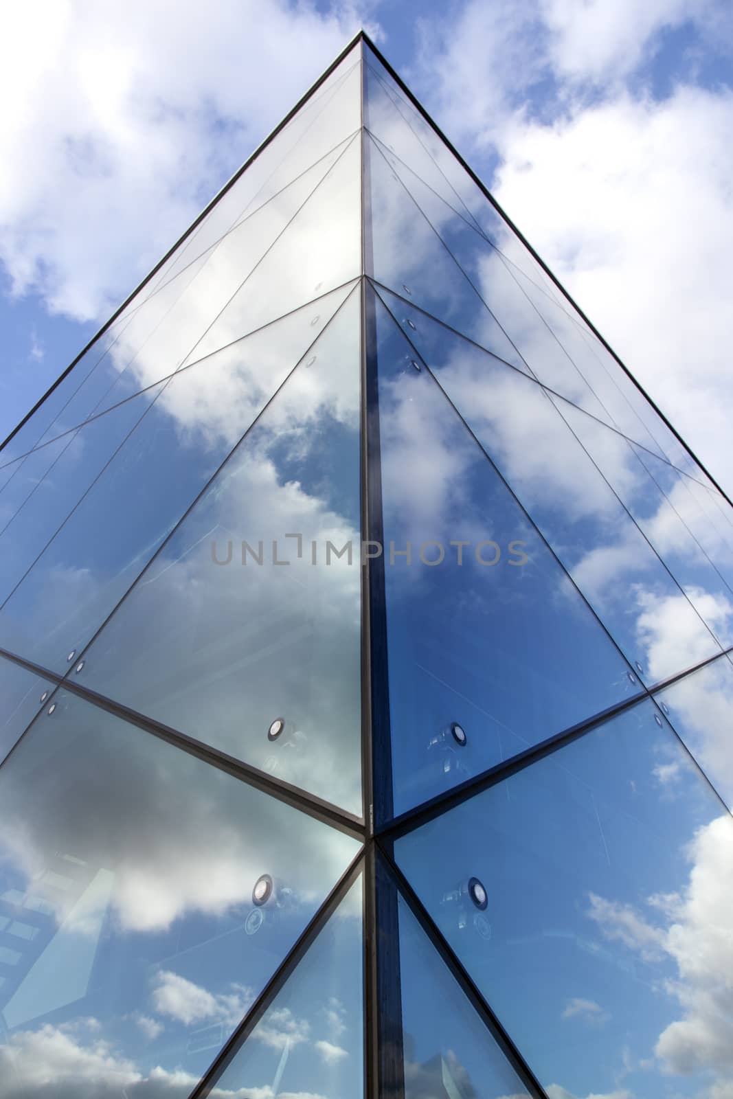 reflexions of clouds and  sky in facade of modern building by ahavelaar