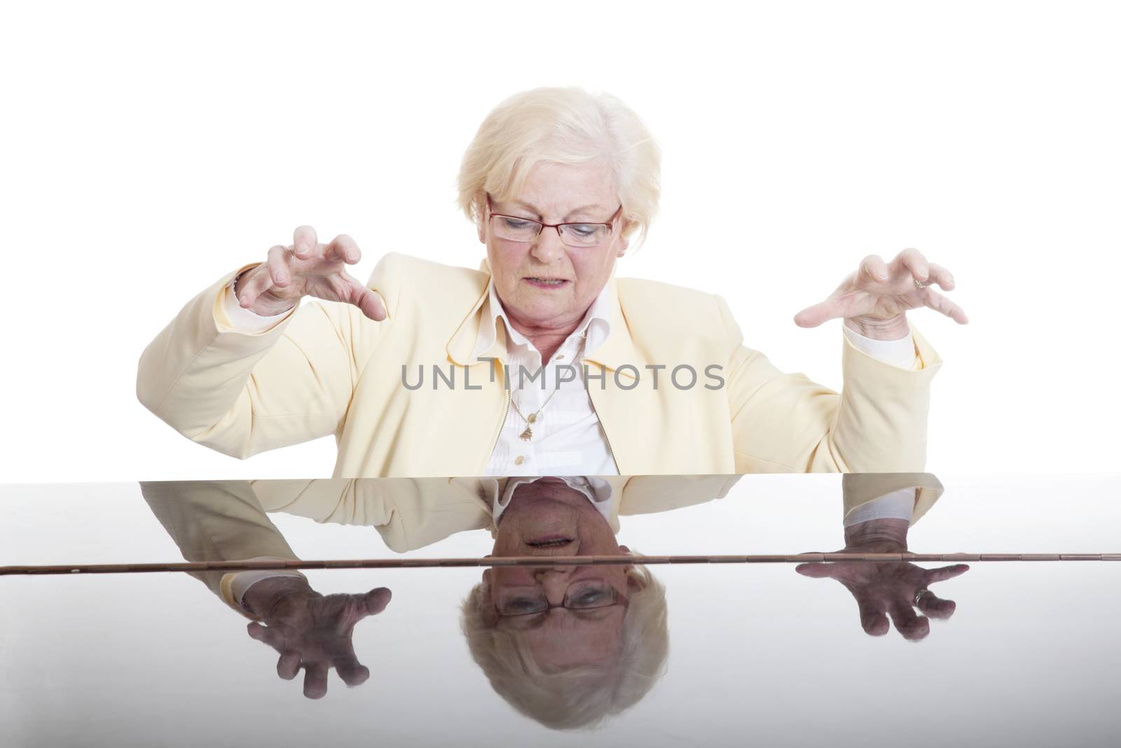 elderly lady in yeloow playing the grand piano in studio with white background