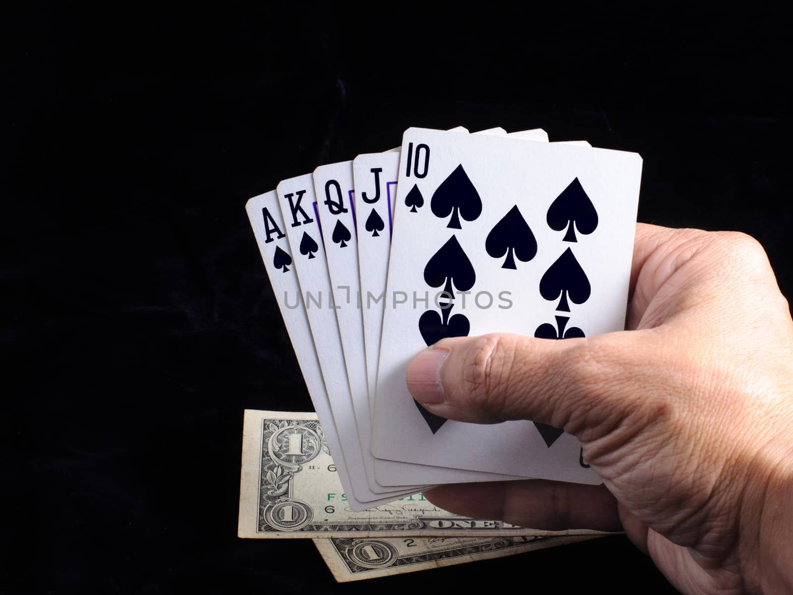 Flush royal cards on hand with money  isolated on black background 