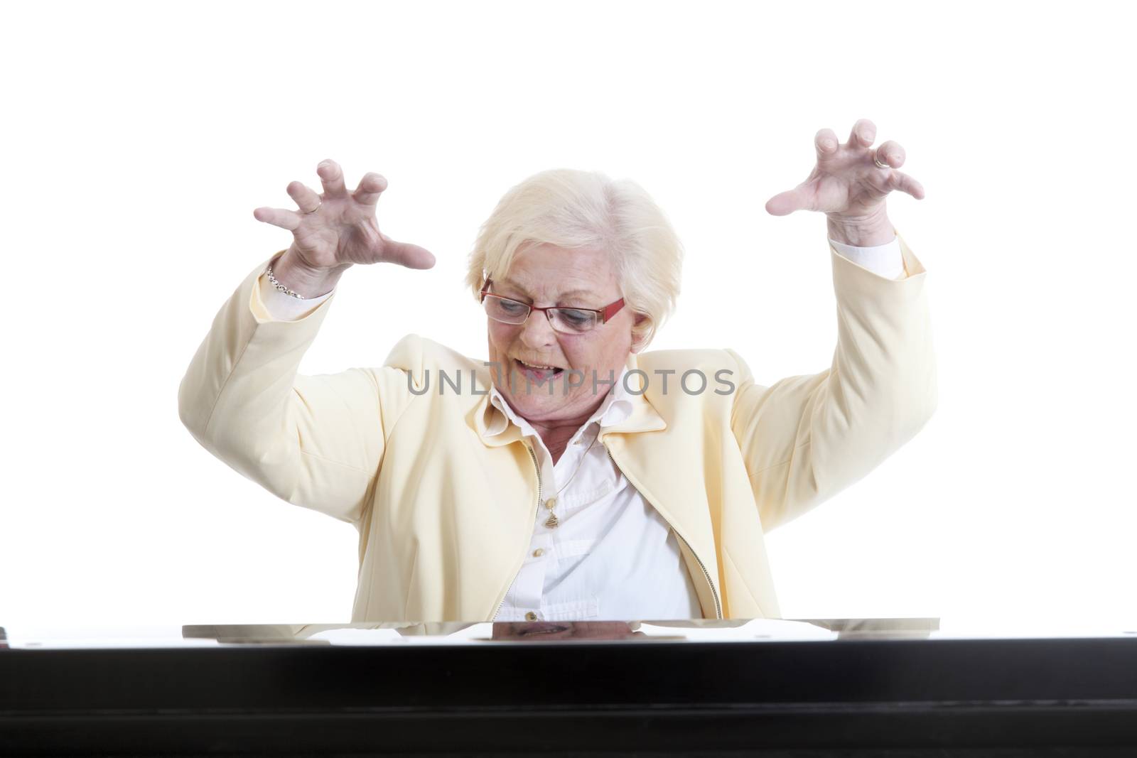 elderly lady in yellow playing the piano in studio with white background