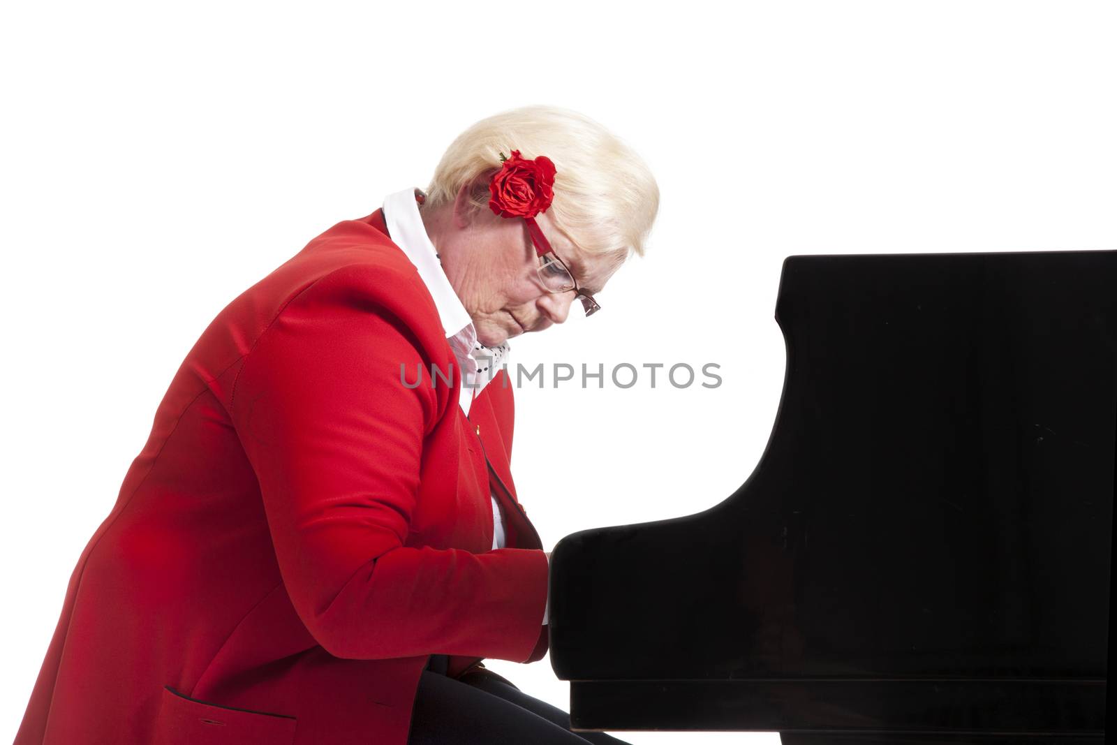 elderly lady in red playing the grand piano in studio with white background