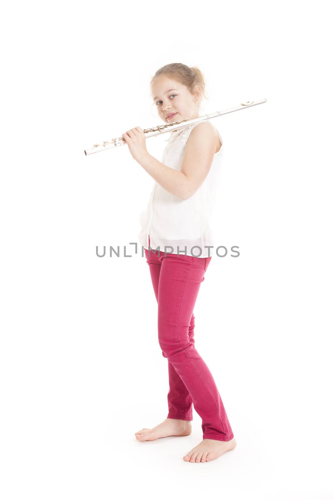 young  girl holding flute standing on the floor of studio with white background