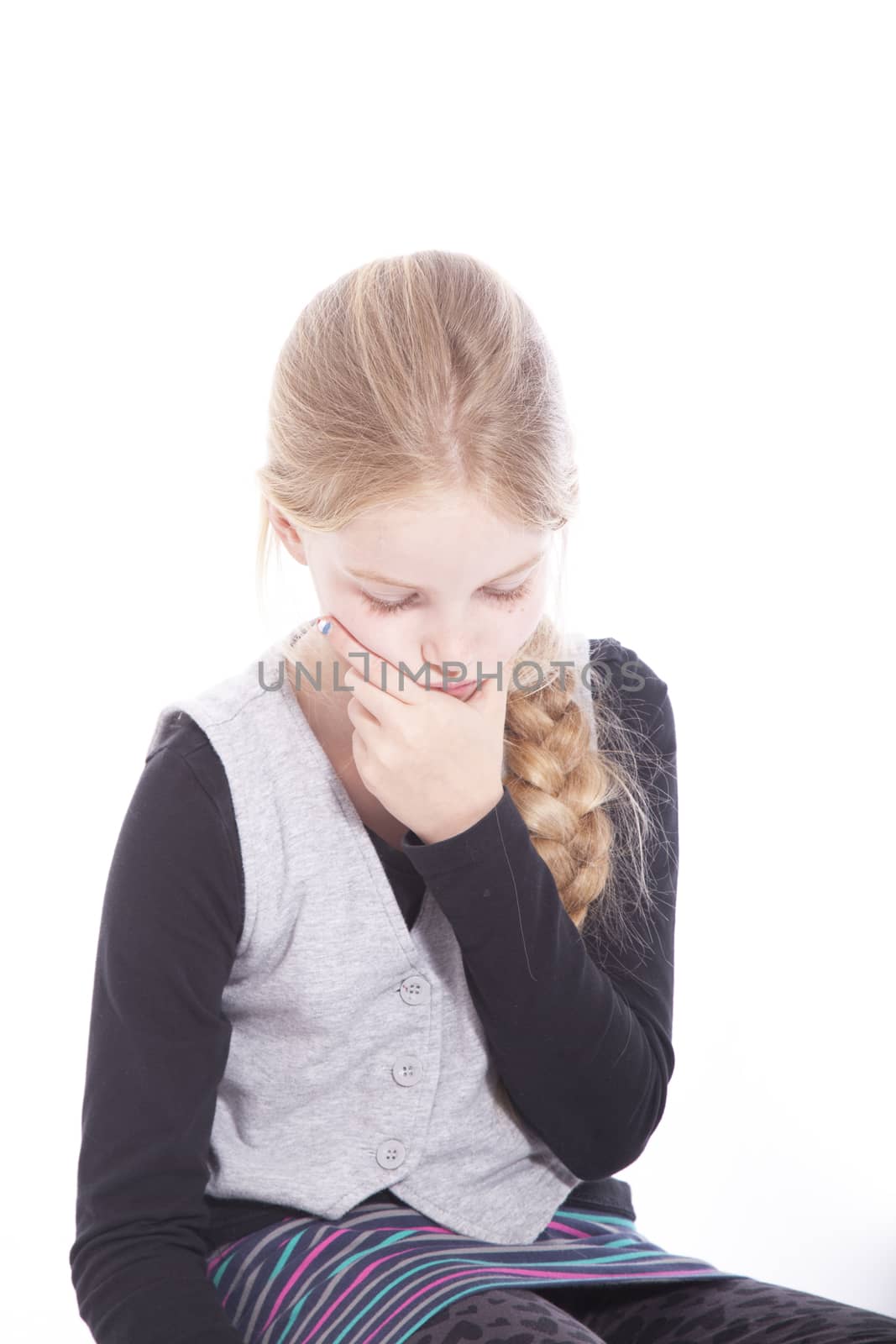 young blond girl thinking on floor of studio against white background