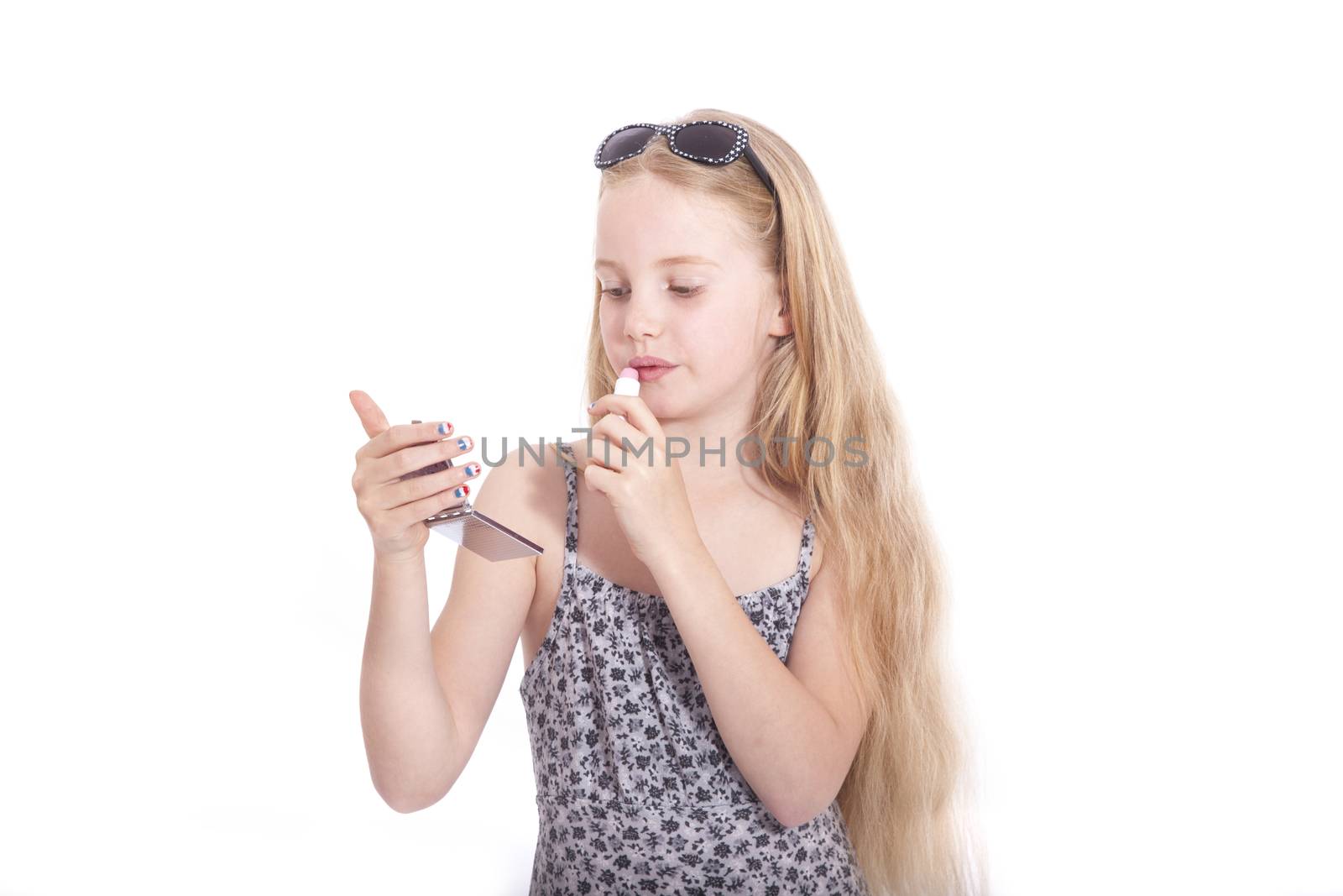 young blond girl applying lipstick in studio against white background