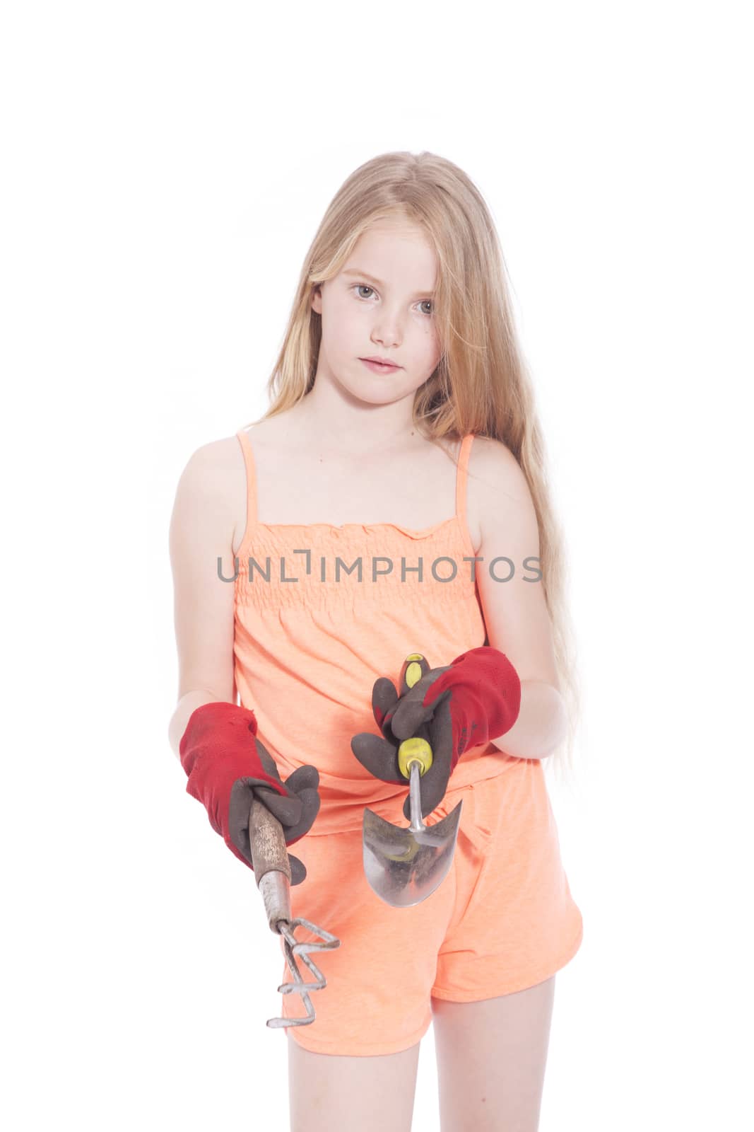 young blond girl with gardening tools in studio against white background