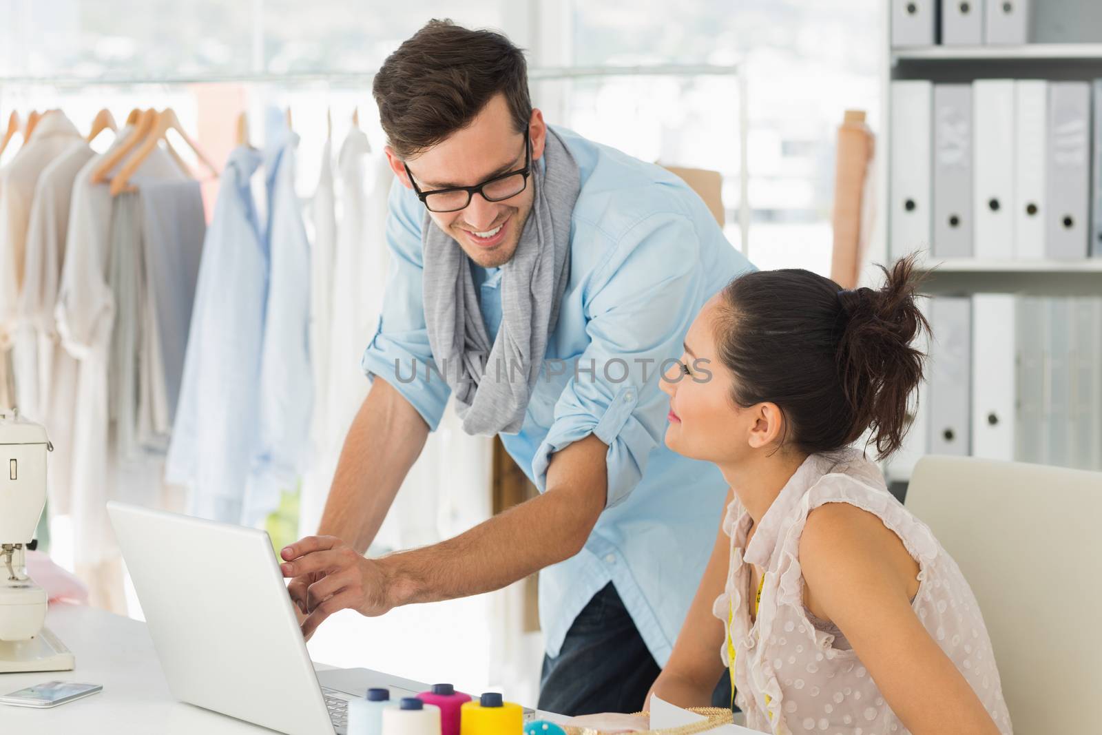 Male and female fashion designers using laptop at work in a studio