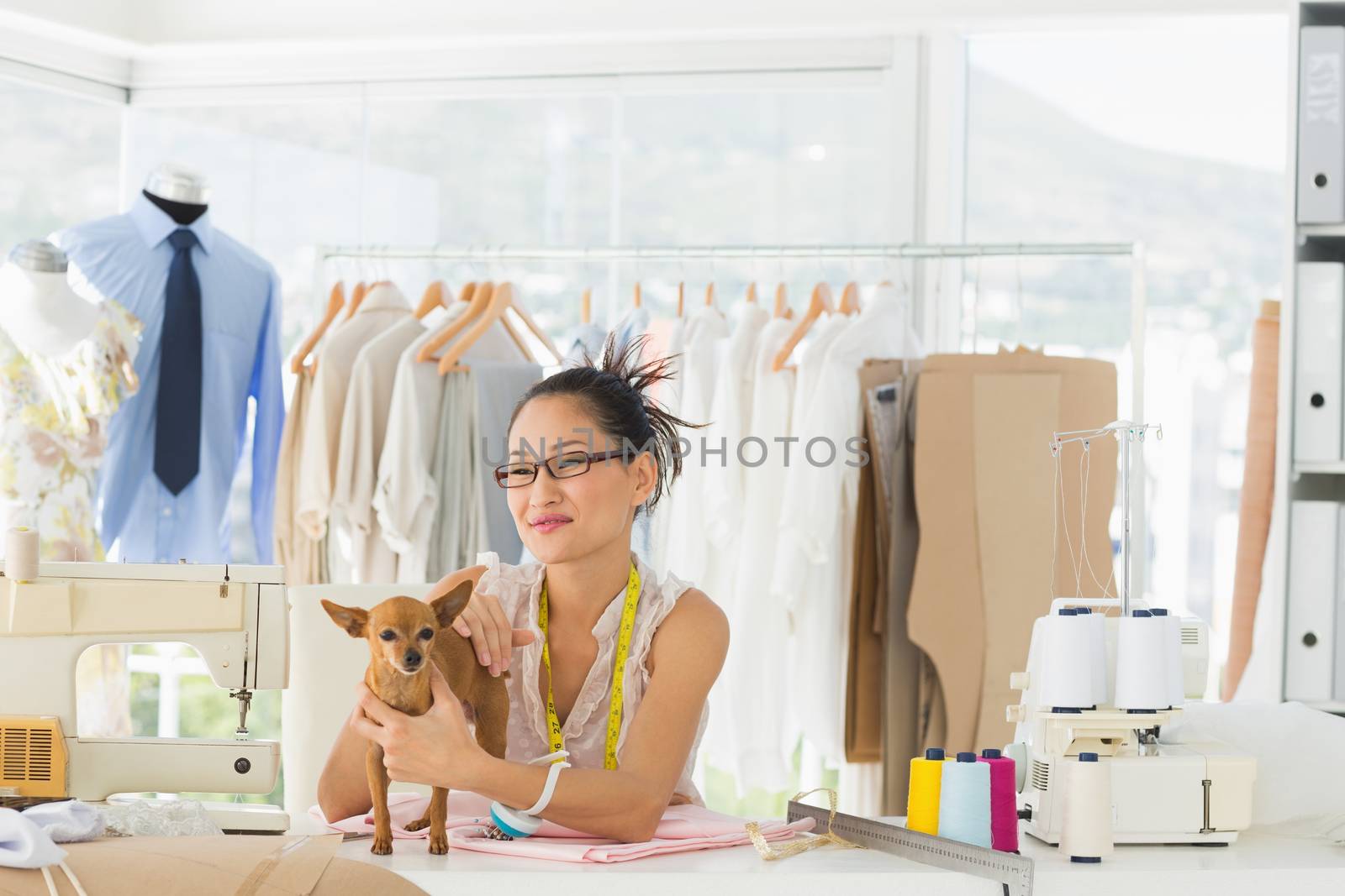 Portrait of a beautiful female fashion designer with chihuahua in the store