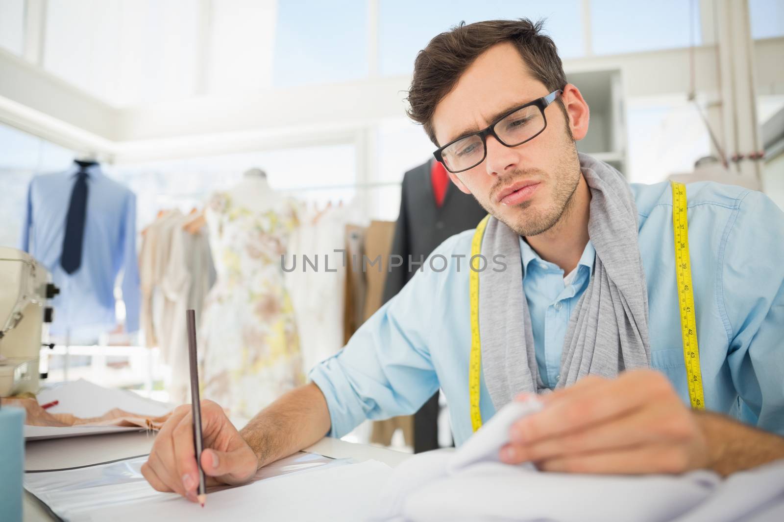 Young male fashion designer working on his designs in the studio