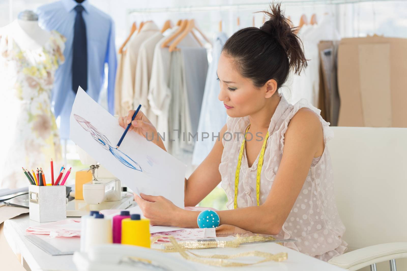 Side view of a young female fashion designer working on her designs in the studio