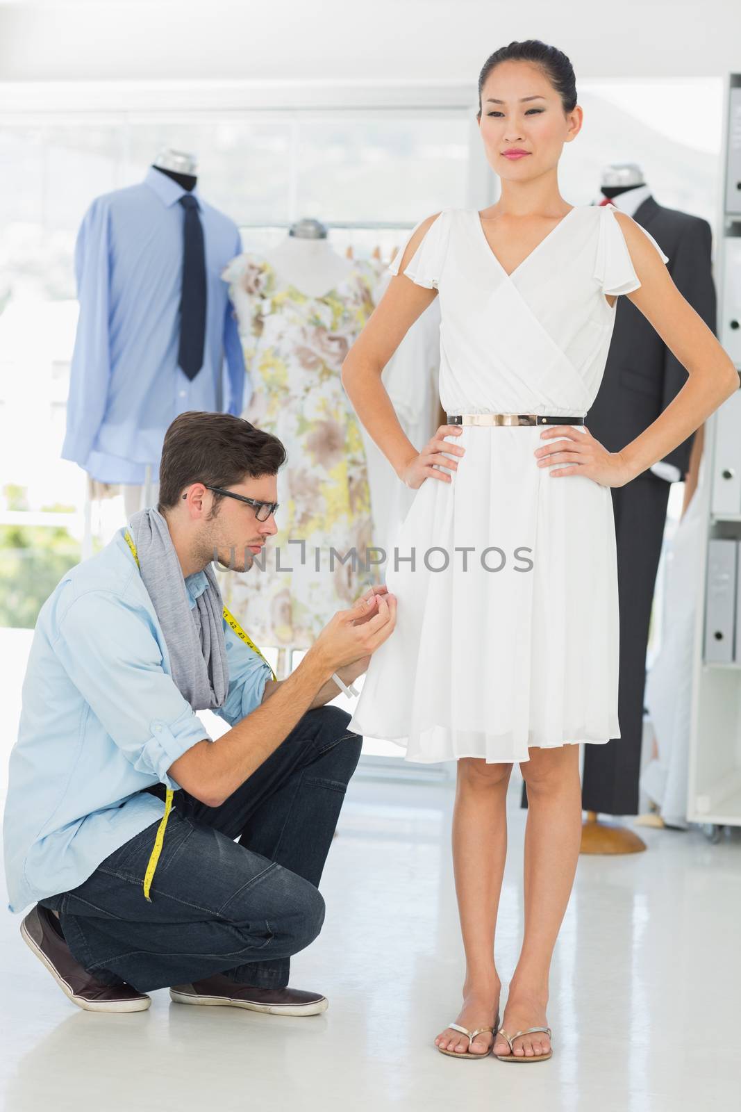Male fashion designer adjusting dress on model in the studio