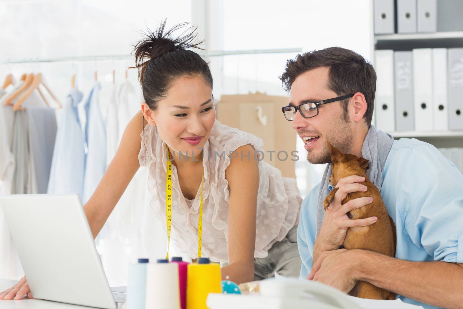 Male and female fashion designers using laptop at work in a studio