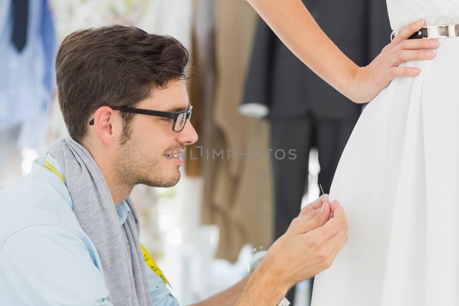 Male fashion designer adjusting dress on model by Wavebreakmedia
