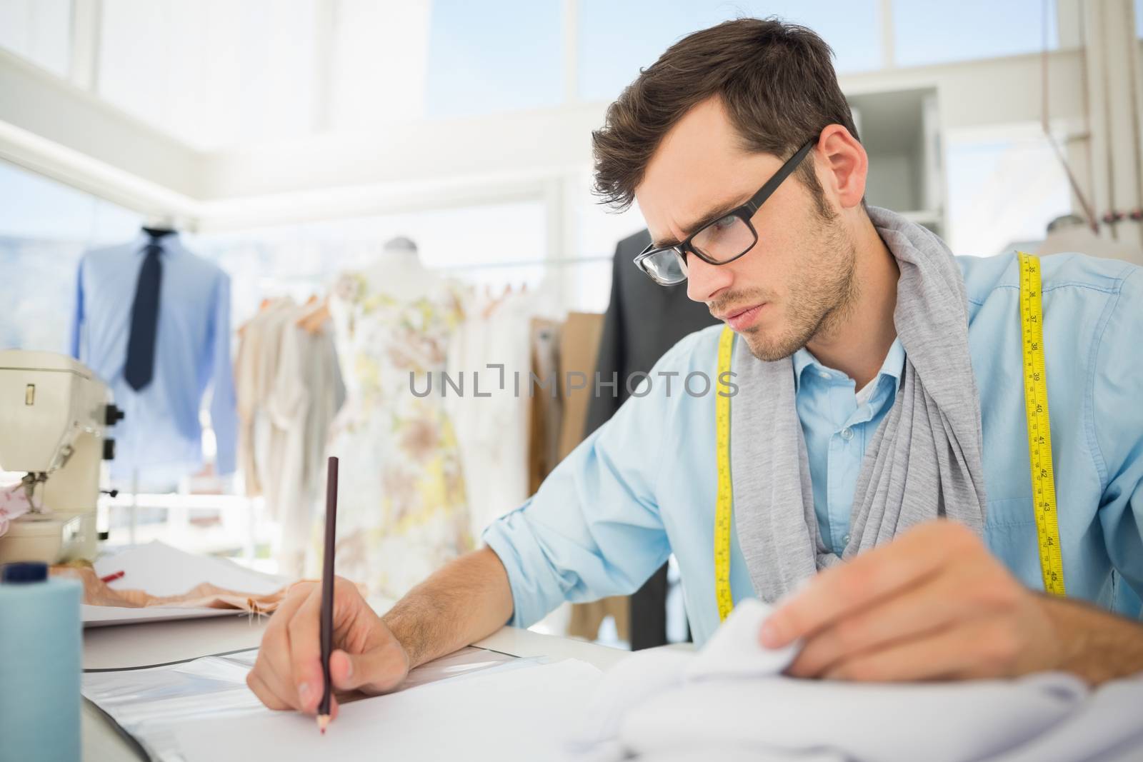 Young male fashion designer working on his designs in the studio