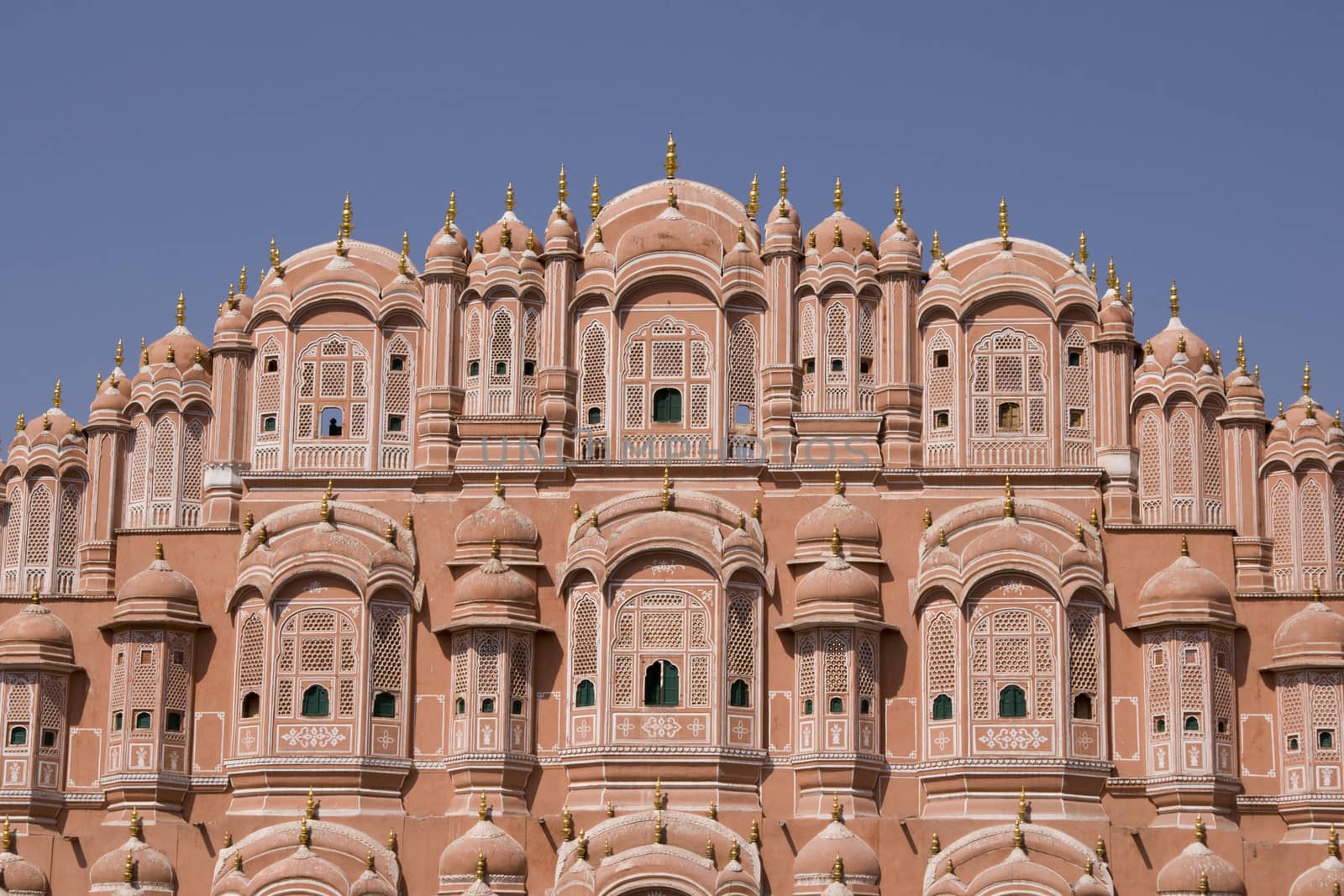 Hawa Mahal or Palace of the Winds. Ornate pink facade built to allow ladies of the Royal Court to look into the street without being seen. Jaipur, Rajasthan, India