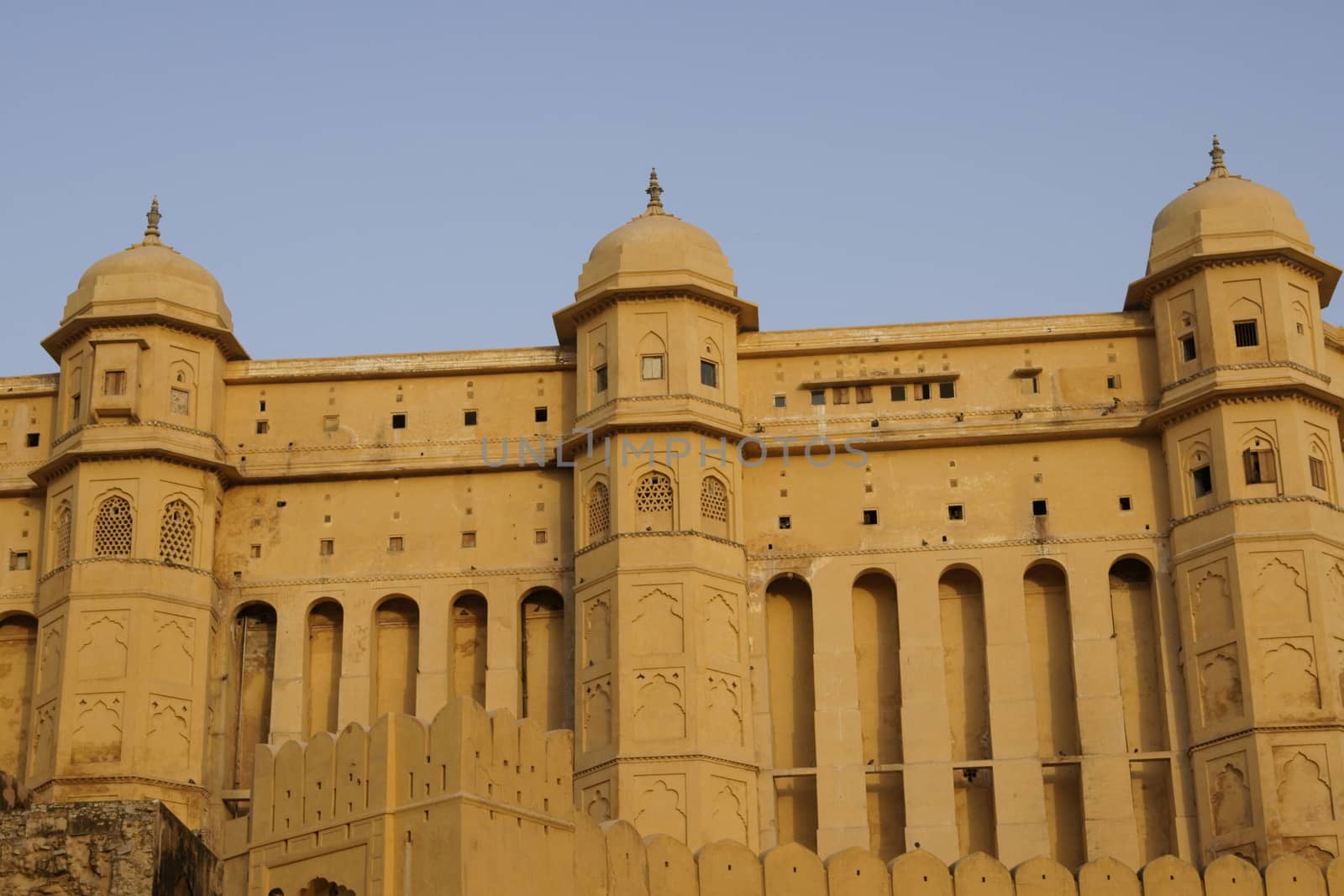 Imposing walls of Amber Fort. Large honey coloured Moghul style building. Jaipur, Rajasthan, India
