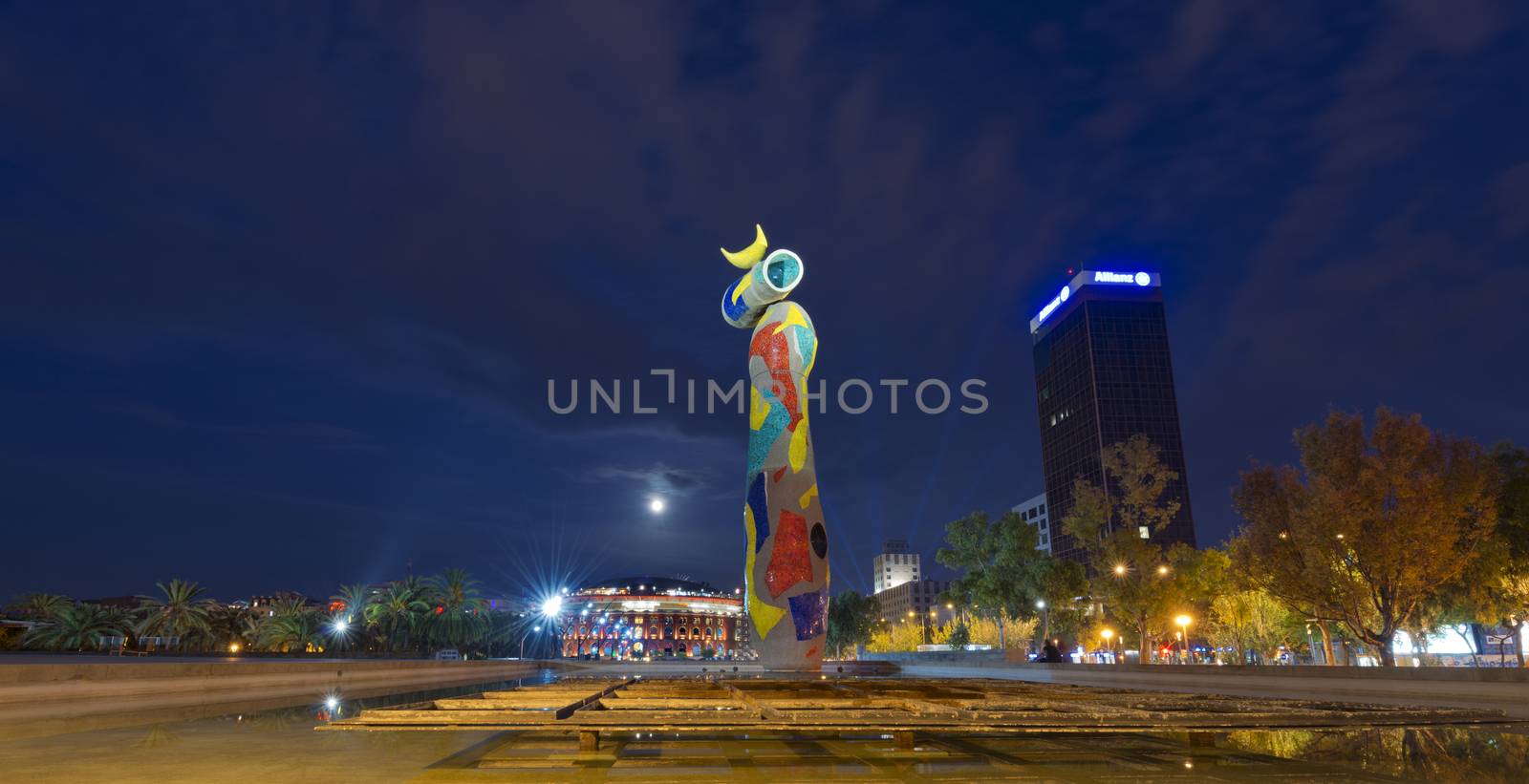 BARCELONA, SPAIN - JUN 12, 2014: Dona i Ocell (Woman and Bird) of Joan Miro (1893-1983) realized by ‪Joan Gardy Artigas‬ (1983) at night in the Park Joan Miro. In the background the Bullring Arenas