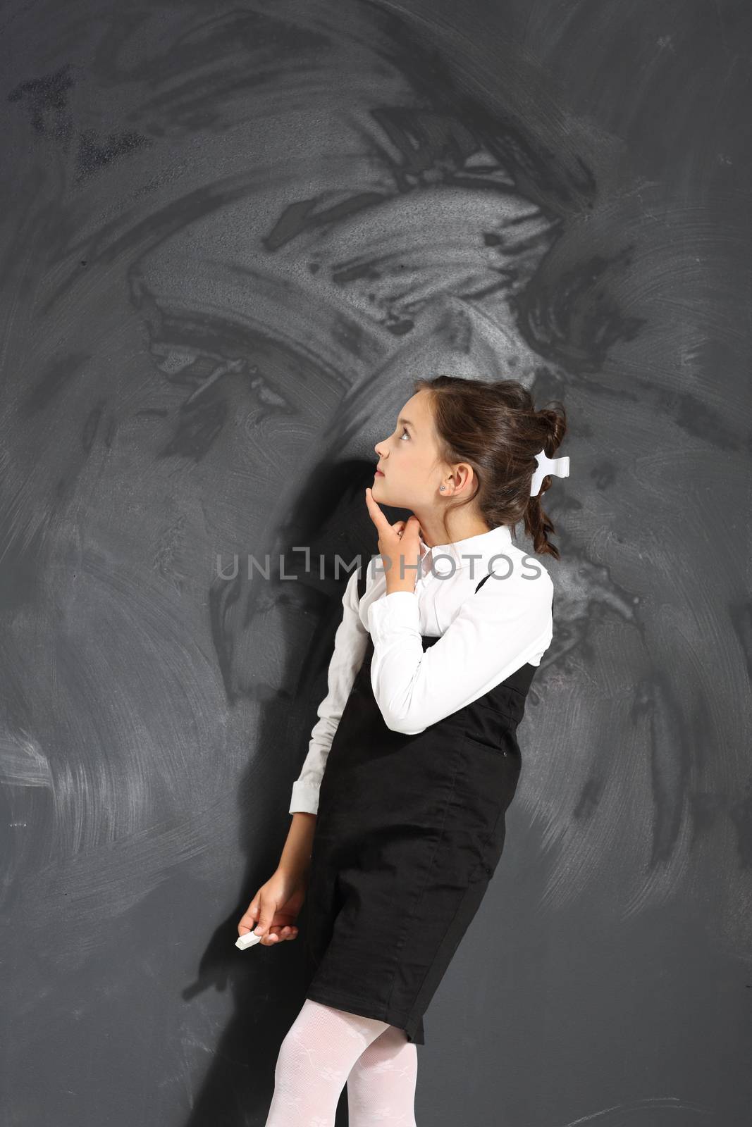 Cute little girl standing by a black school board