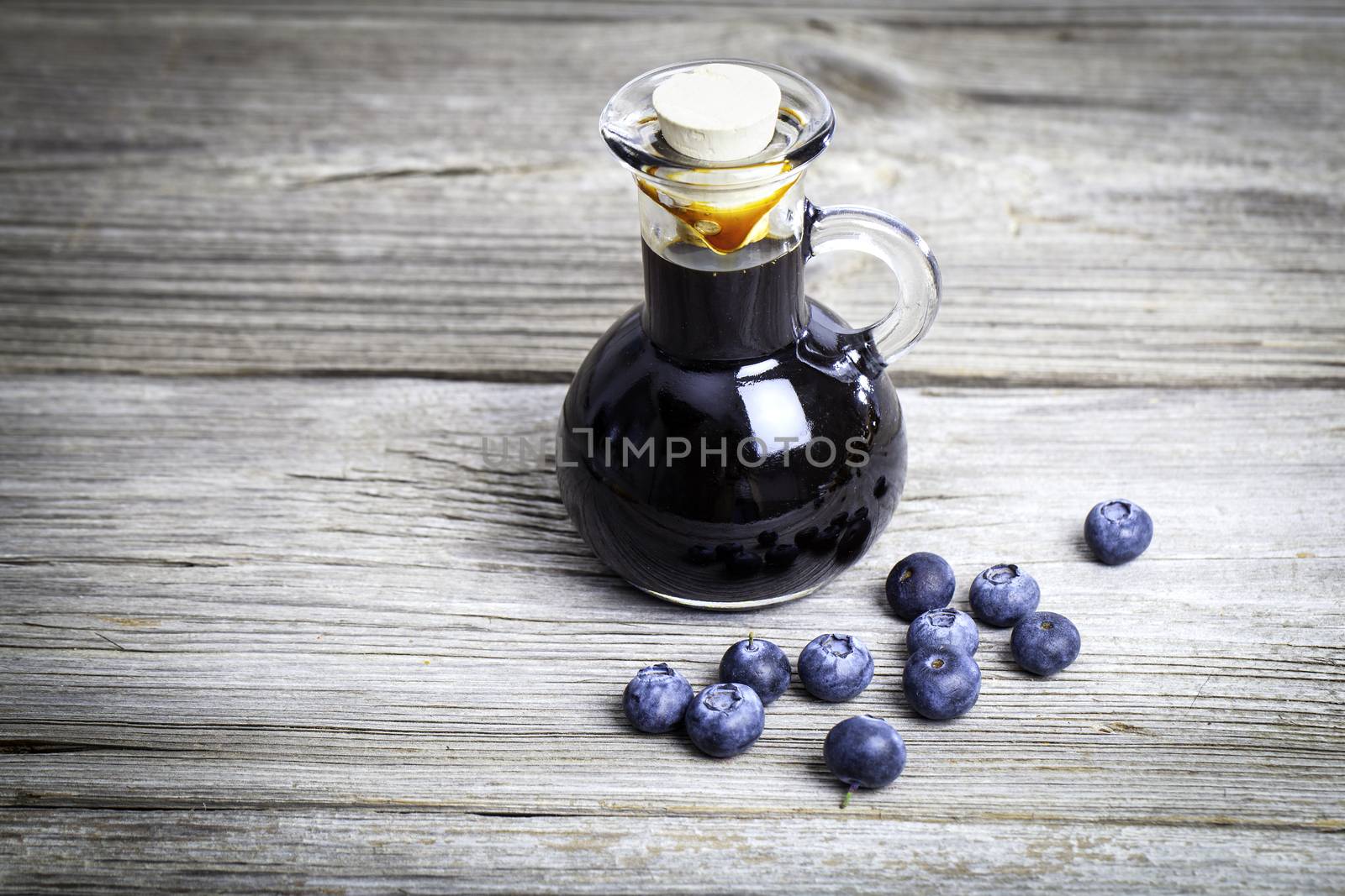 blueberry syrup in glass bottle or mixture, on wooden background.