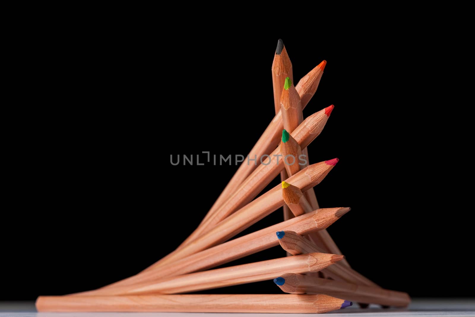 creatively stacked pencils of different colors on black