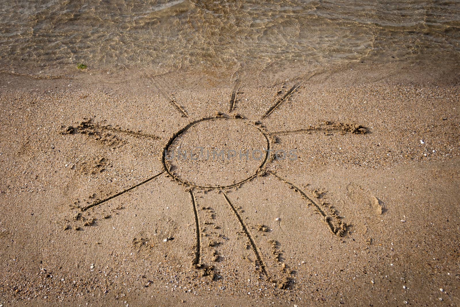 drawing of a sun on sandy beach with water